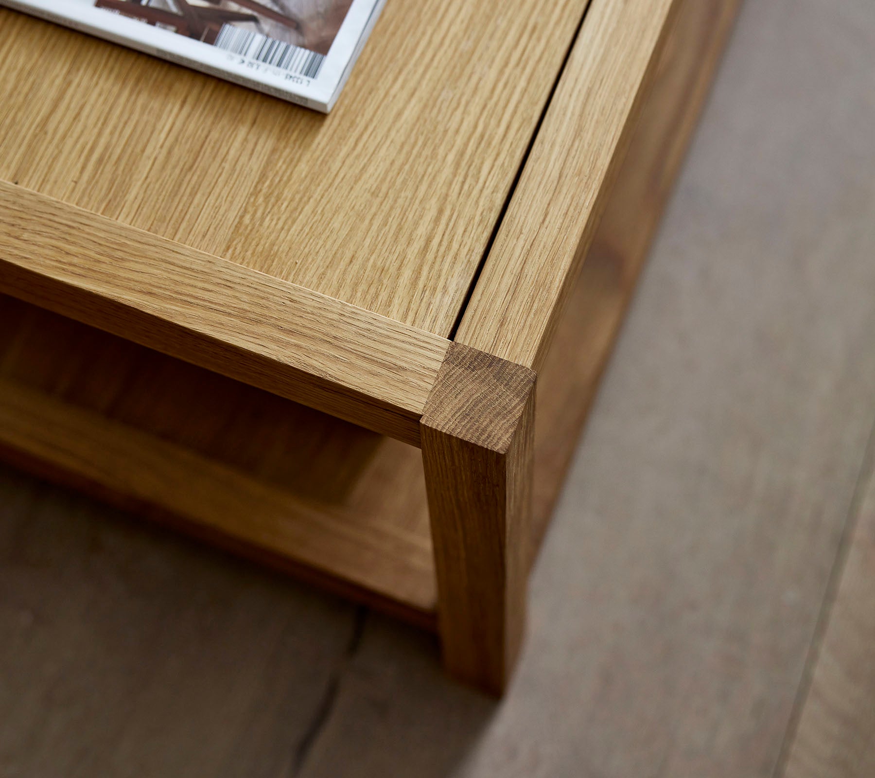 Trekaffebord med et rent design, med et magasin plassert oppå og en minimalistisk nederste hylle for ekstra lagring.
