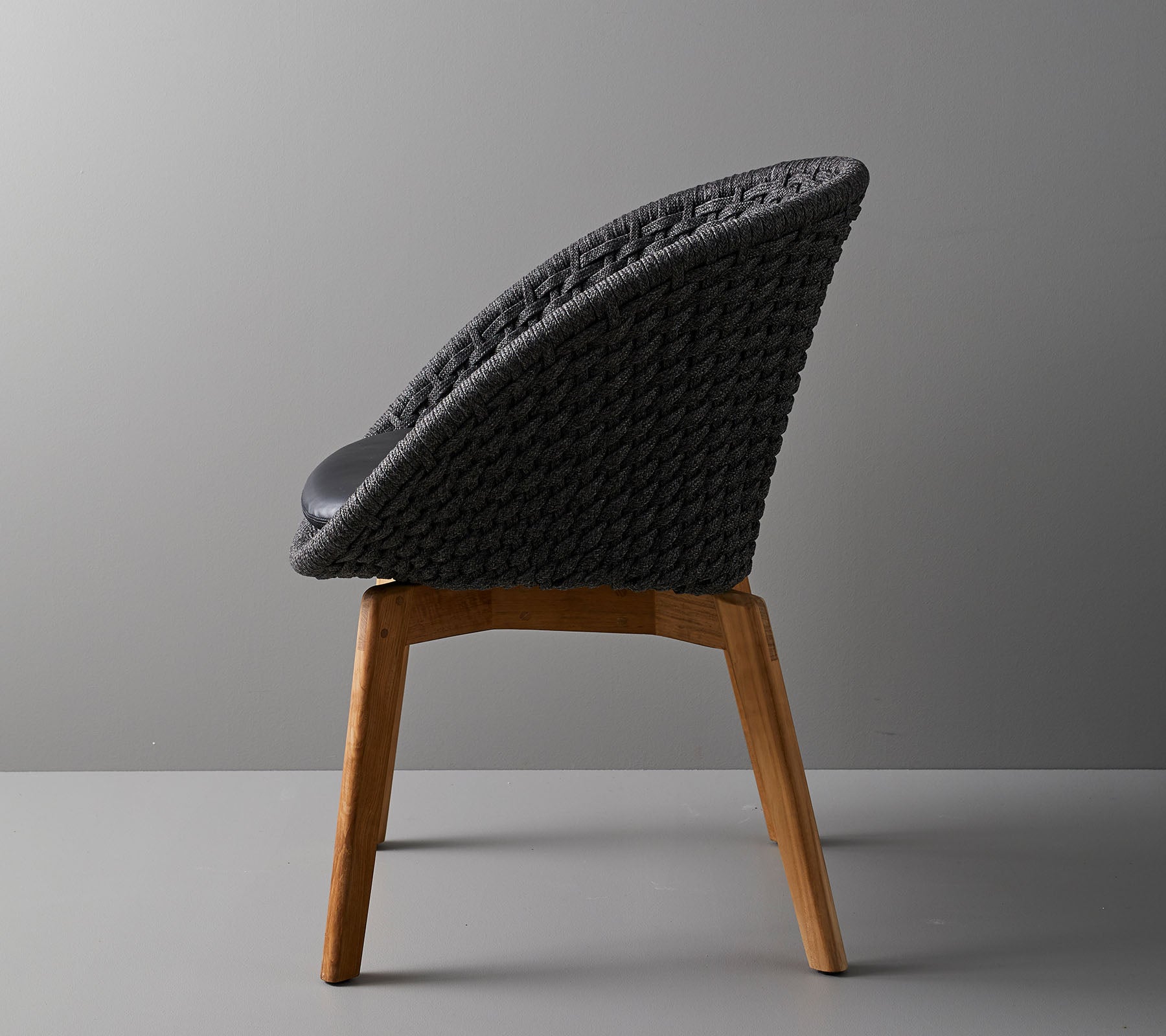 Stilig stol med vevet ryggstøtte og treben, som tilbyr et moderne design ideelt for moderne rom.
