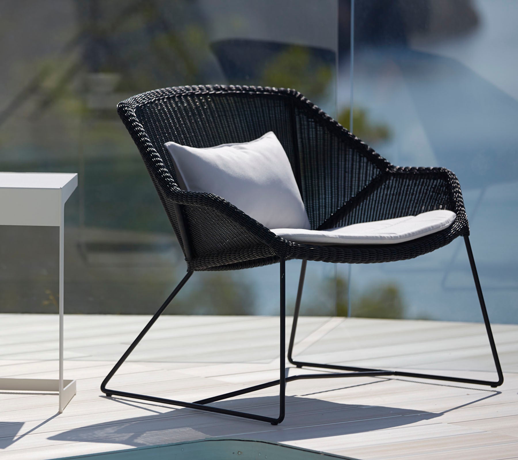 Moderne svart stol med hvit pute i en stilfull ute-lounge-setting.