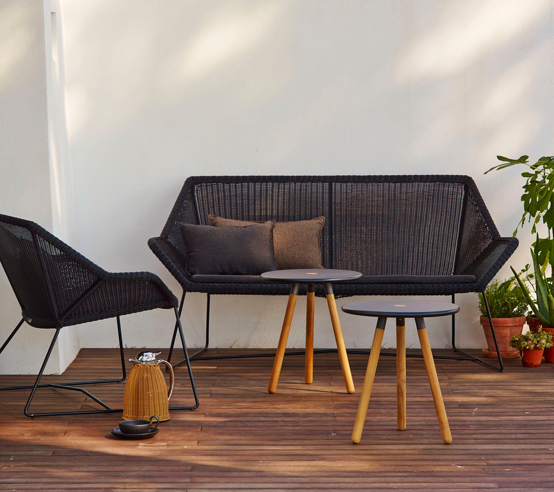 Moderne sitteopplegg med en svart sofa med puter, en matchende stol og et rundt bord med treben.