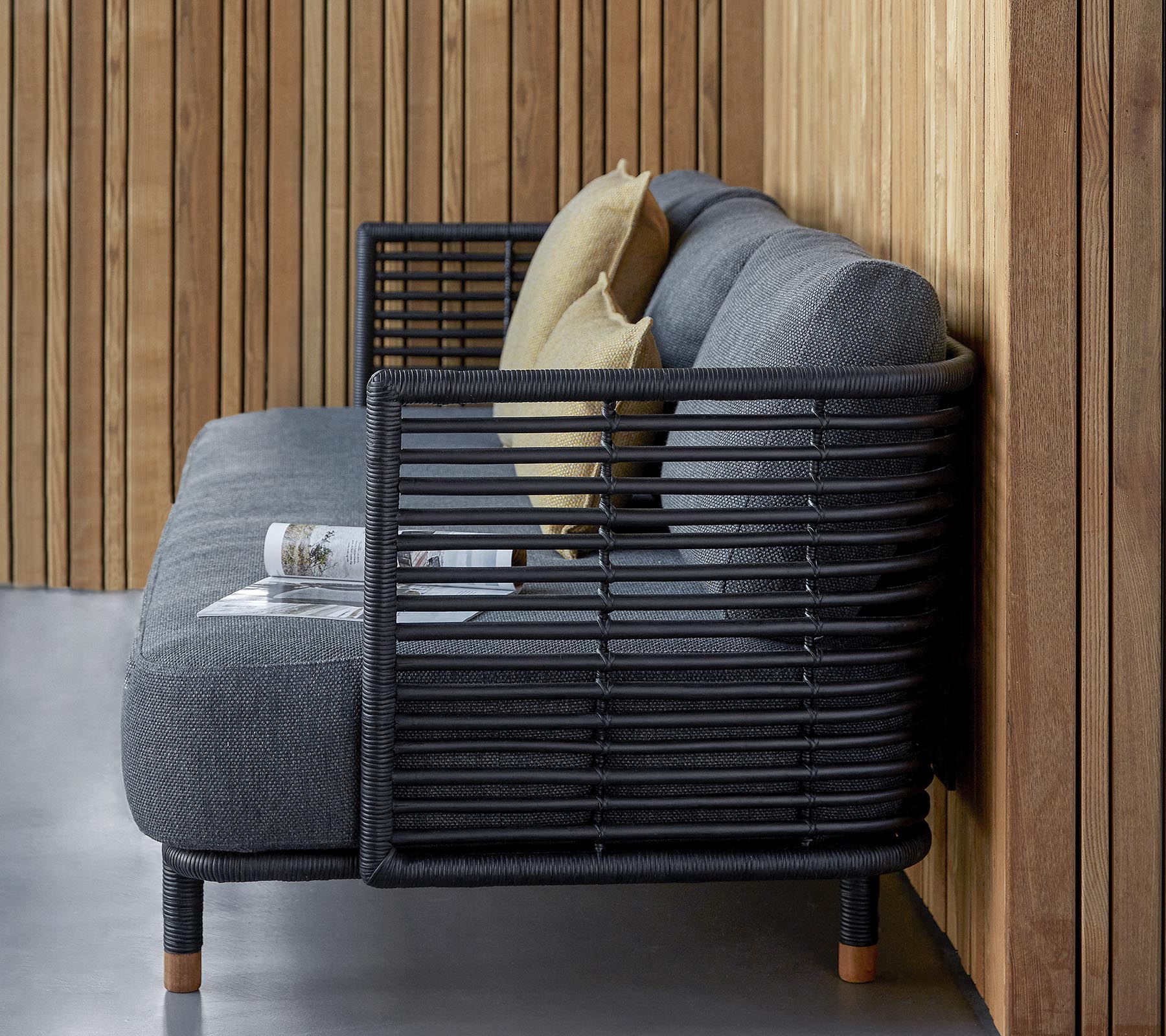 Stilig sofa med et slankt design i teksturert grå stoff og dekorative puter, komplementert av en moderne lamellramme.
