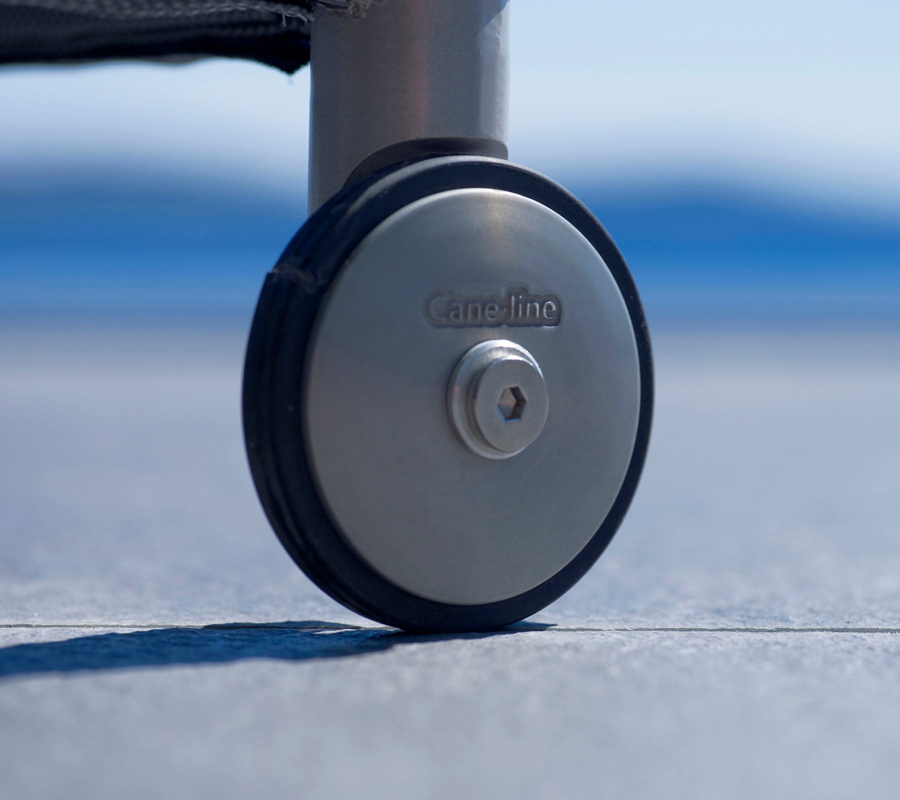 Nærbilde av et slitesterkt hjul med metallfinish og et logo, designet for enkel mobilitet og stabilitet på ulike overflater.