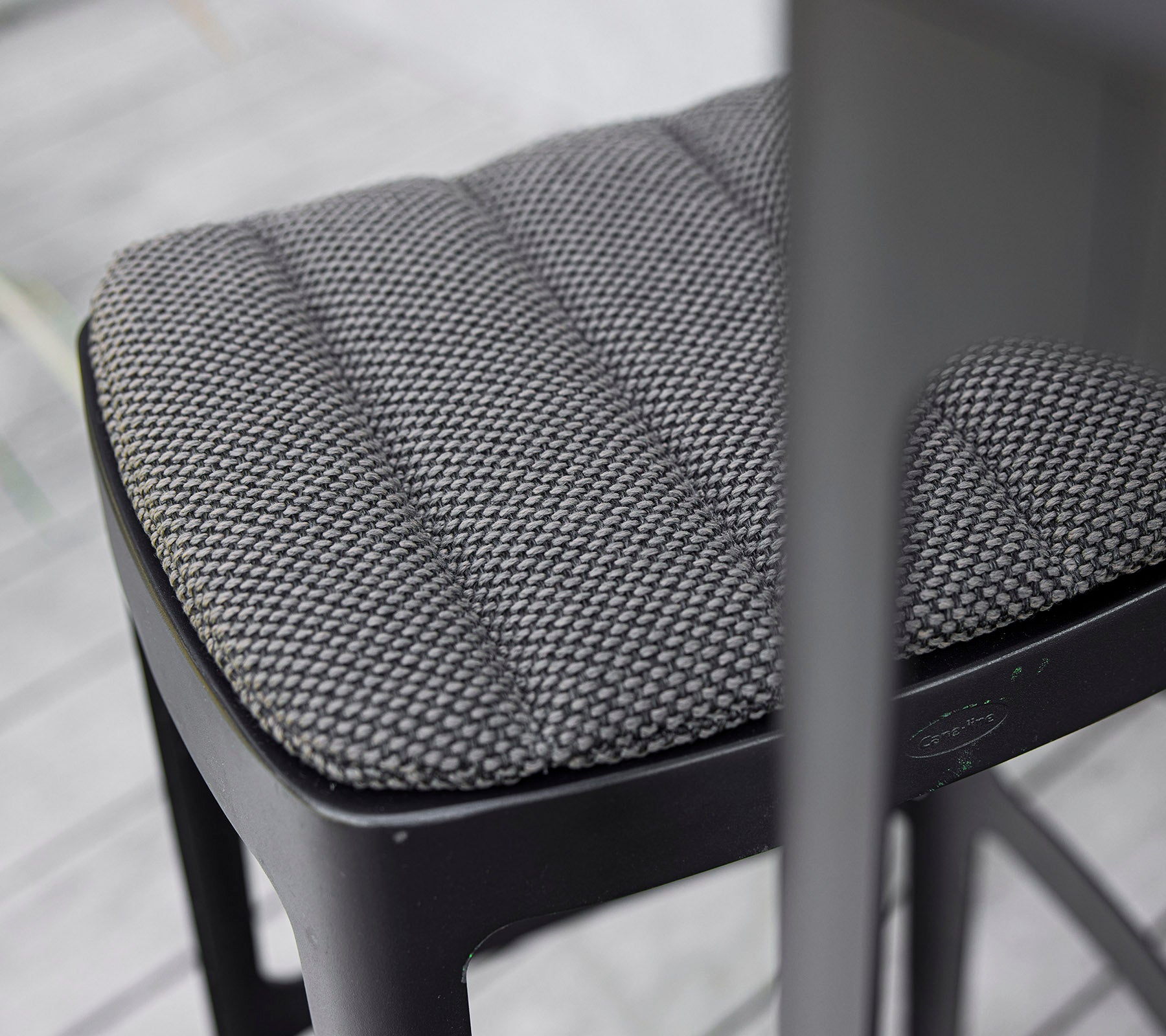Nærbilde av en teksturert svart stolsete med en quiltet design som viser moderne håndverk og oppmerksomhet på detaljer.