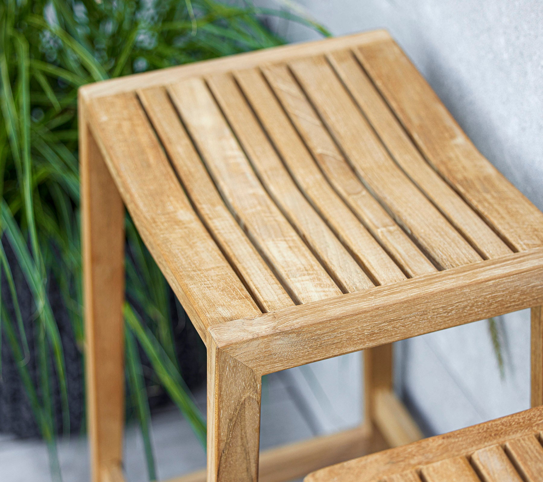 Et stilrent trebord med et lamelløst toppdesign, med en lys finish som kompletterer den omkringliggende grønnskapen.