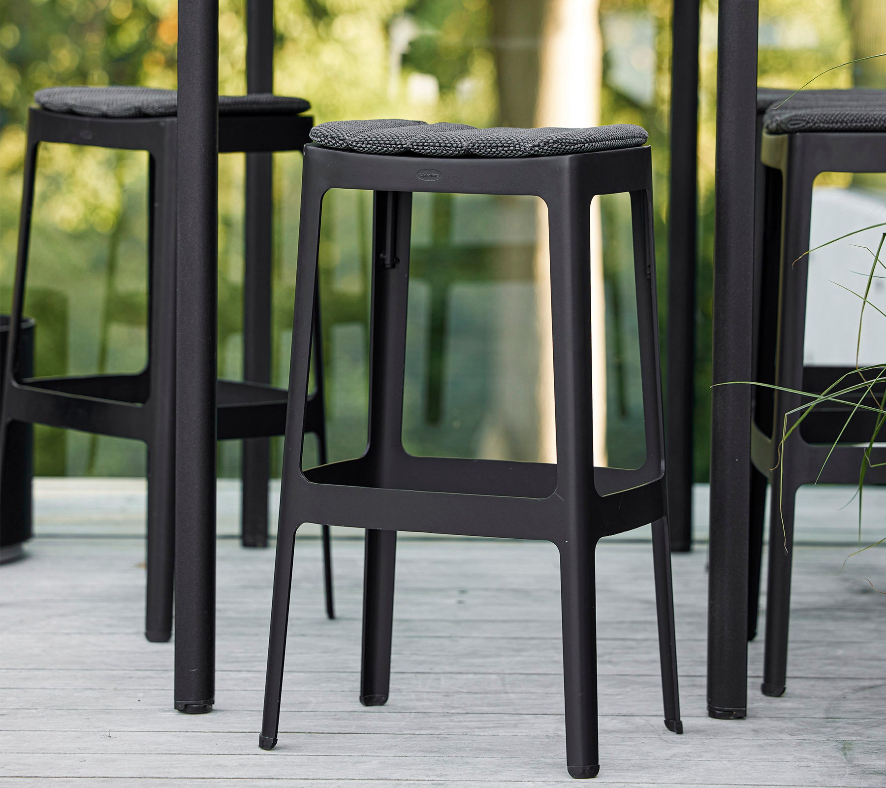 Sorte barstoler med minimalistisk design og polstrede seter, tett samlet og viser en moderne estetikk.