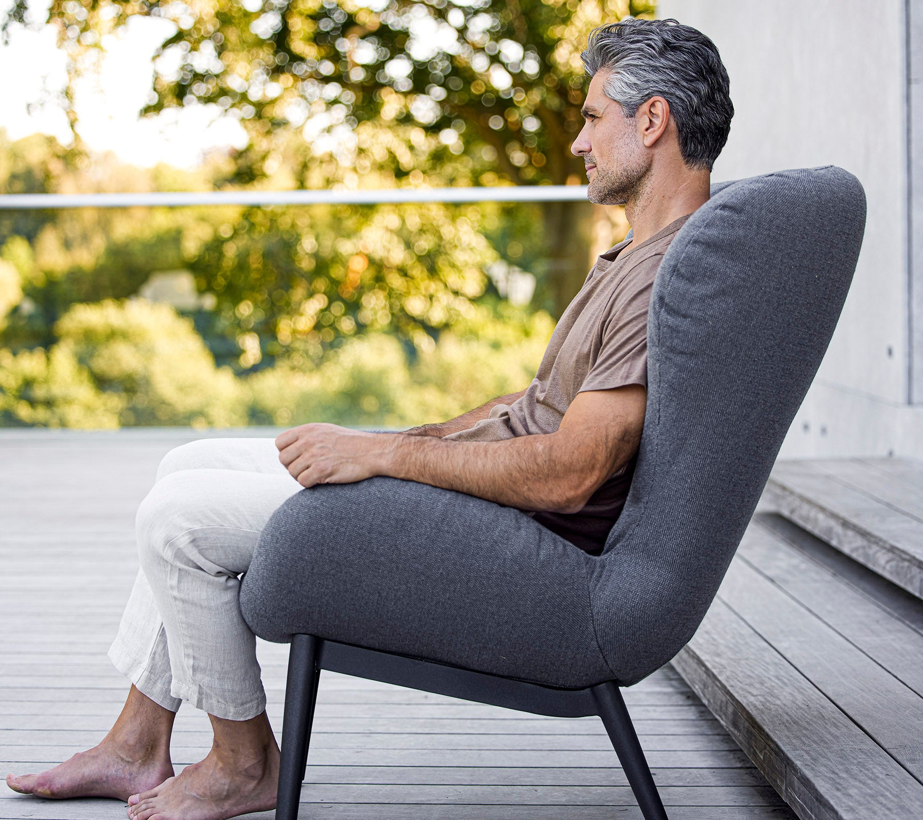 Mann som sitter komfortabelt i en moderne stol med et strømlinjeformet design, som viser myk polstring og en elegant, minimalistisk form.