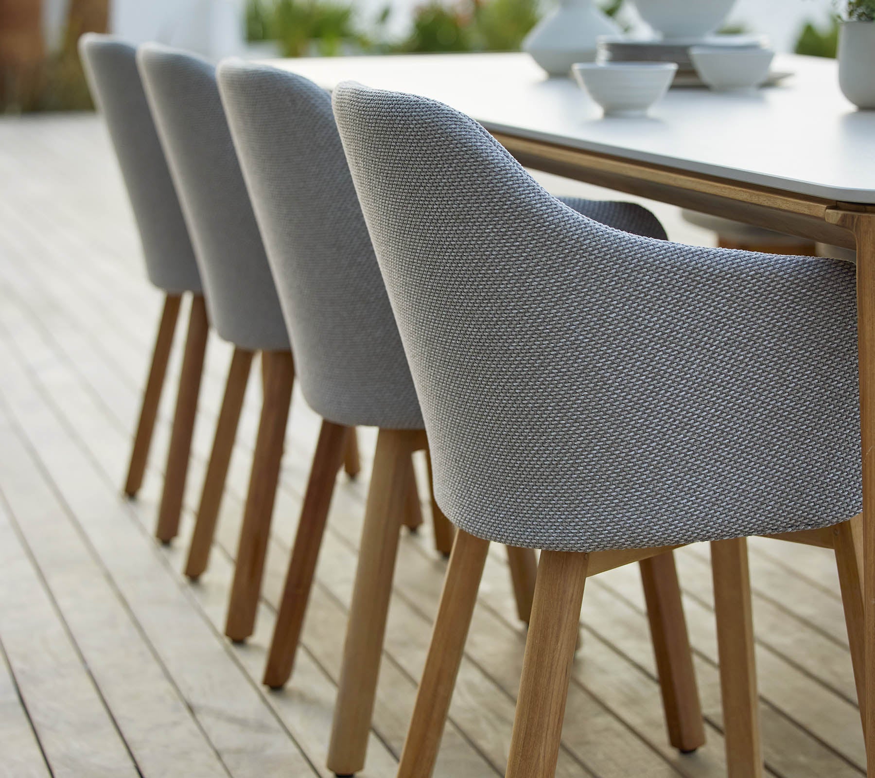 En rad med moderne polstrede stoler med treben, pent ordnet ved siden av et bord som viser et stilig og moderne design.