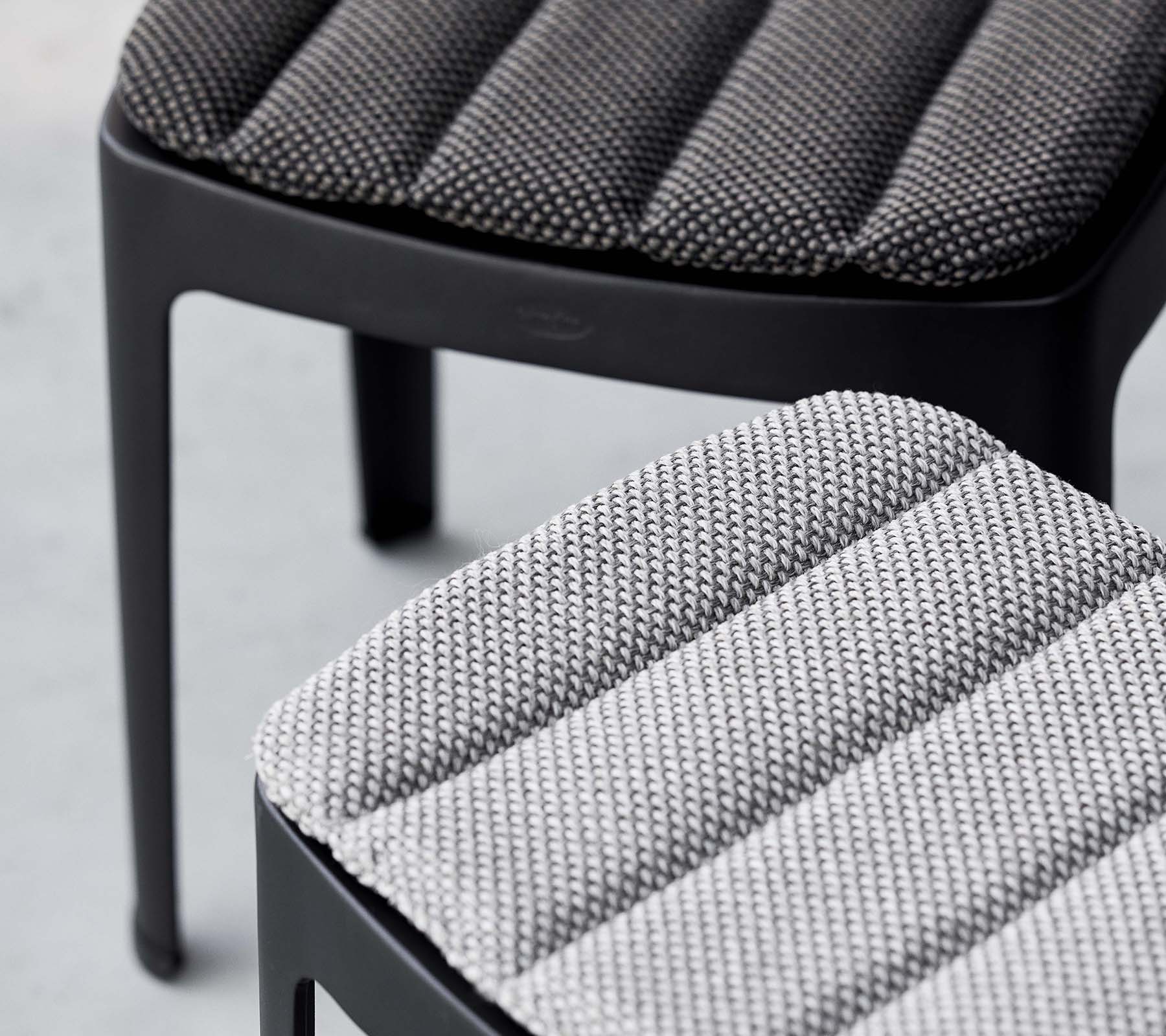 To stilige barstoler med teksturert polstring i kontrasterende gråtoner, som viser et moderne design med slanke linjer.
