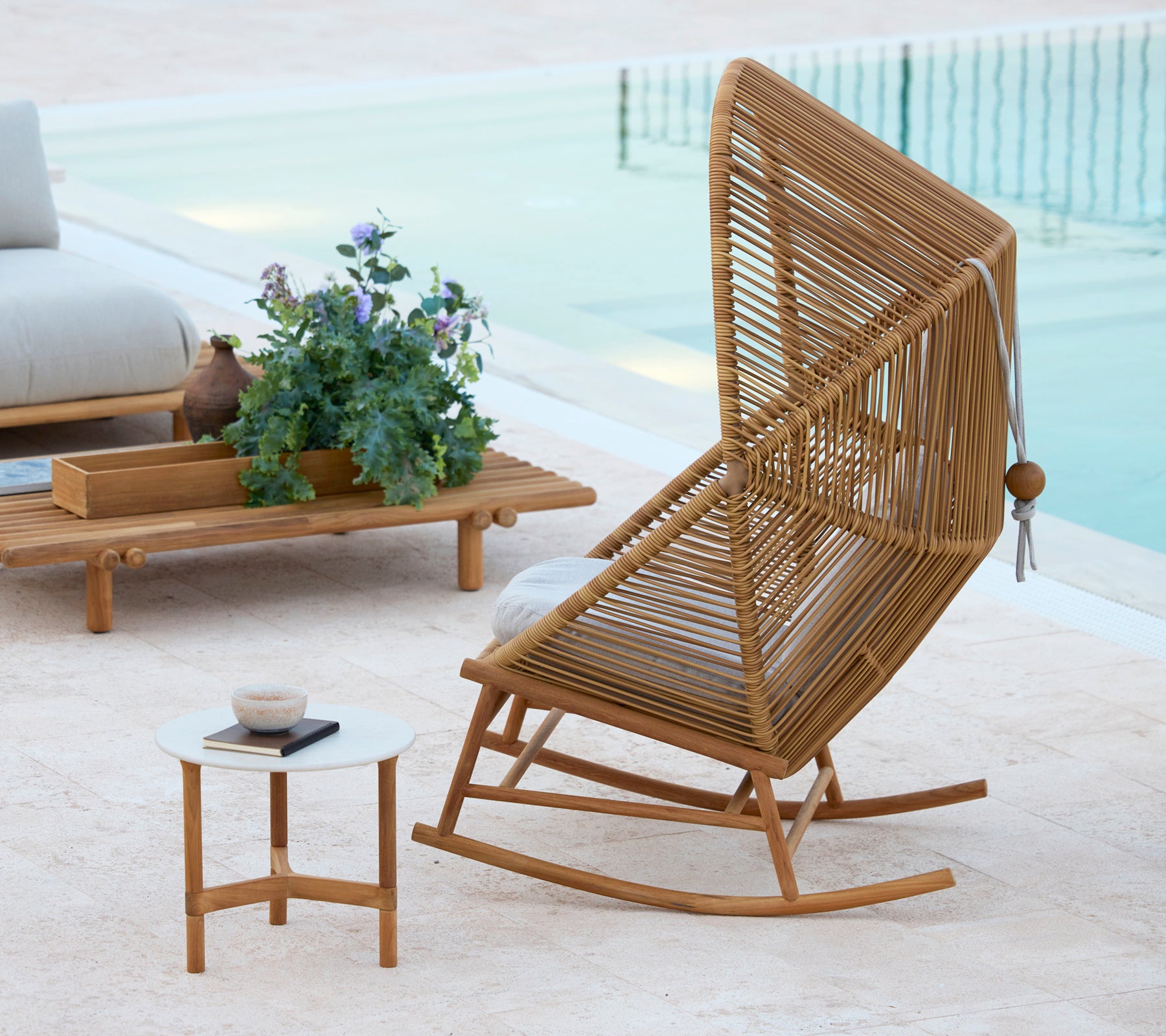 En stilig Hive gyngestol ved siden av et Twist kaffe bord og et Sticks kaffe bord, komplementert med en potteplante.