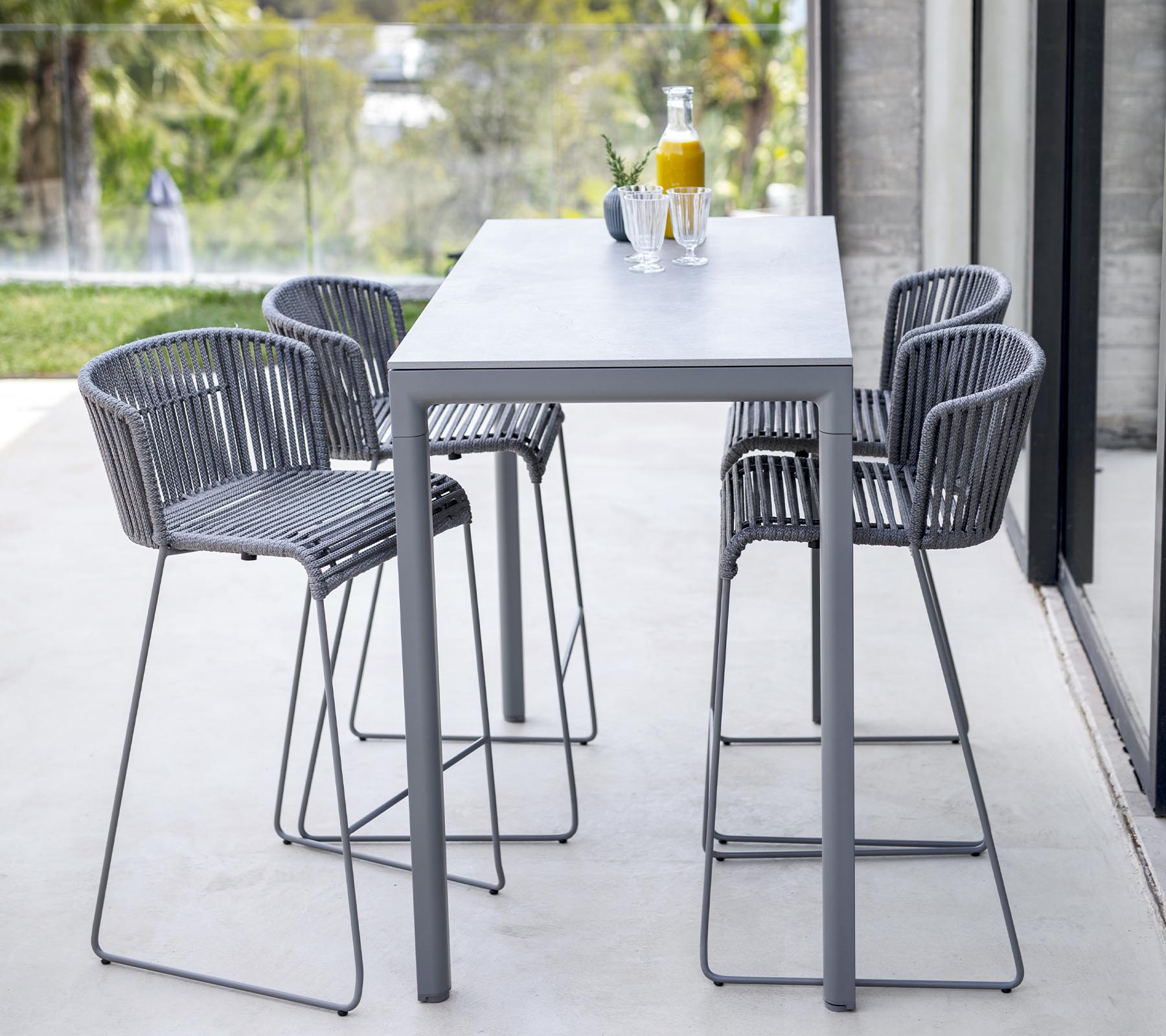 Moderne spisestuesett med et elegant bord og fire høyryggede stoler med minimalistisk design, ideelt for uformelle sammenkomster.