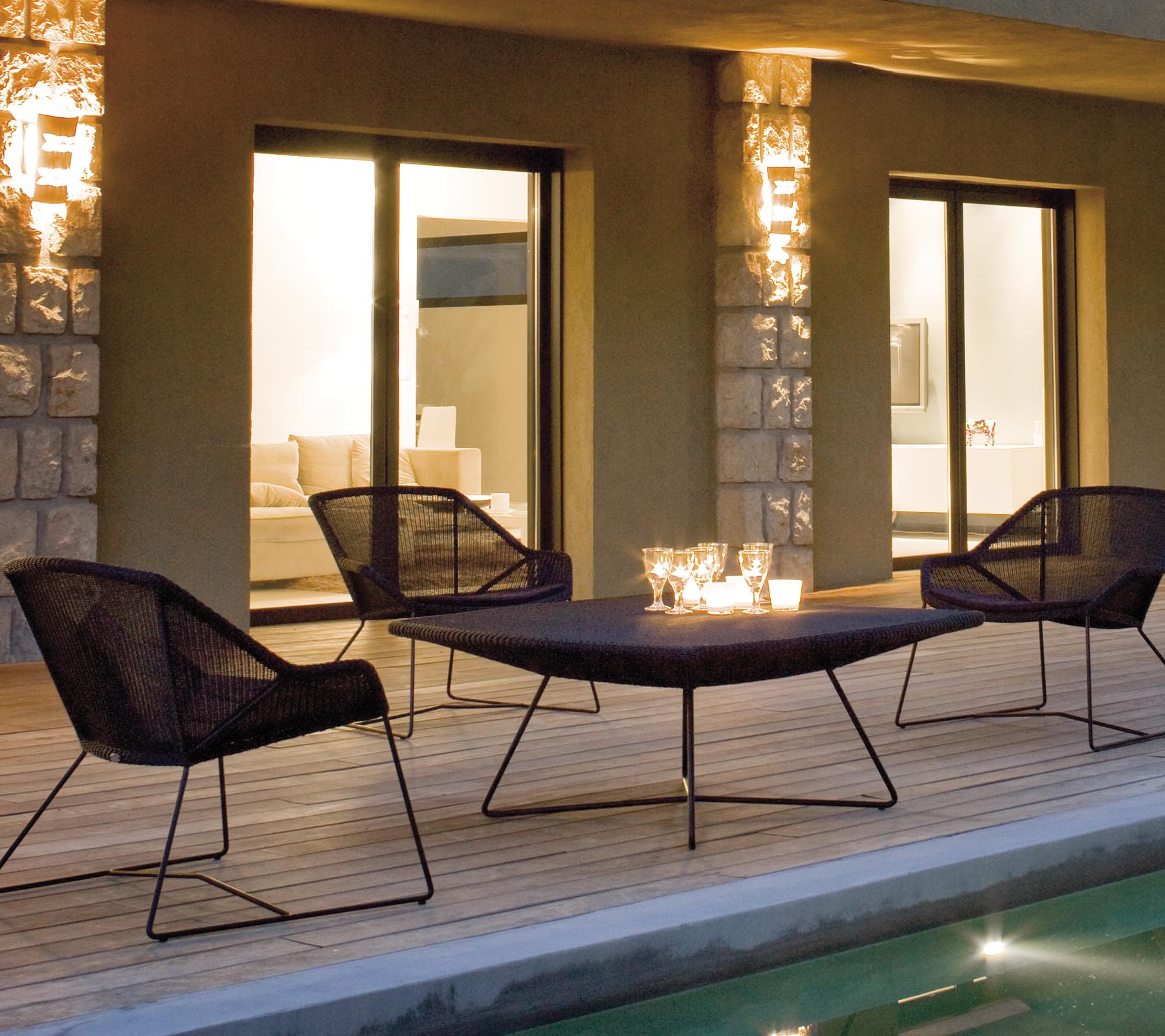 Et stilrent lounge seating arrangert med fire svarte nettstoler rundt et elegant bord, opplyst av myk ambient belysning.
