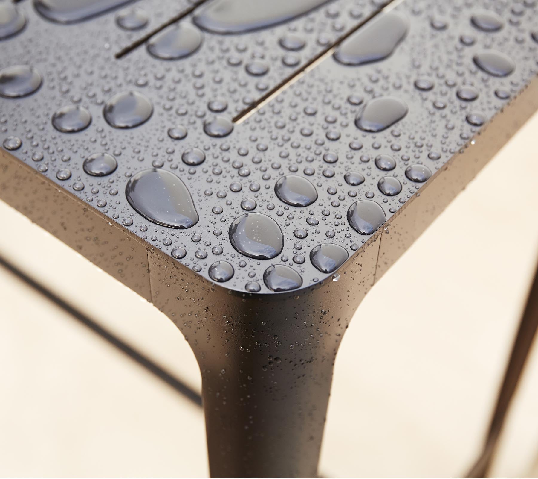Nærbilde av en strukturert overflate med vanns droplets, som fremhever det strømlinjeformede designet og detaljene i materialet.