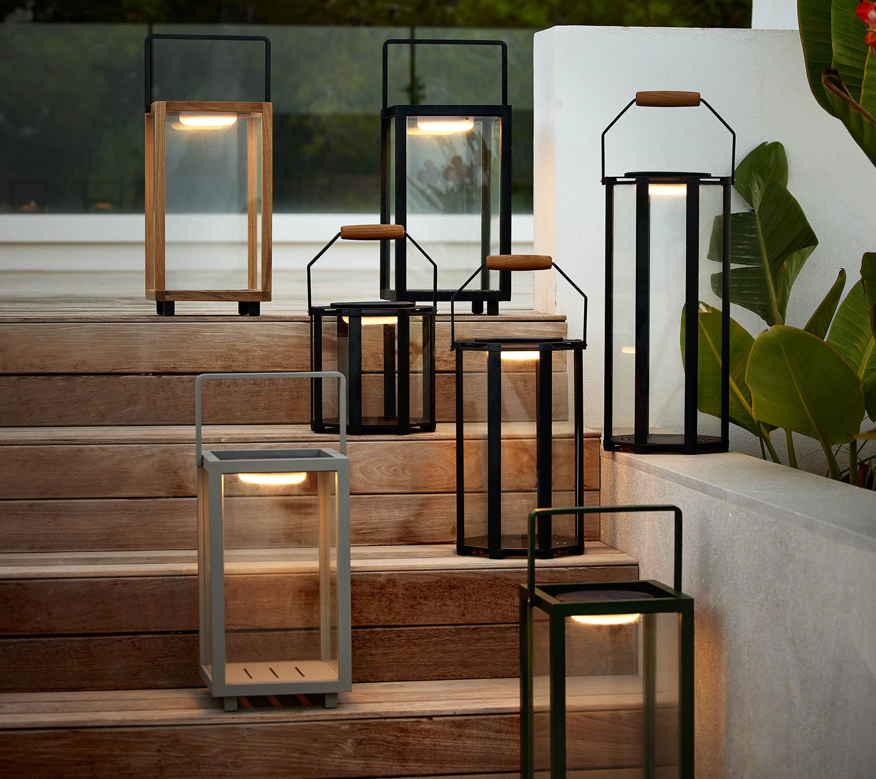 En samling av moderne lanterner i forskjellige stiler og farger, arrangert på en trapp, som fremhever deres elegante design og varme belysning.