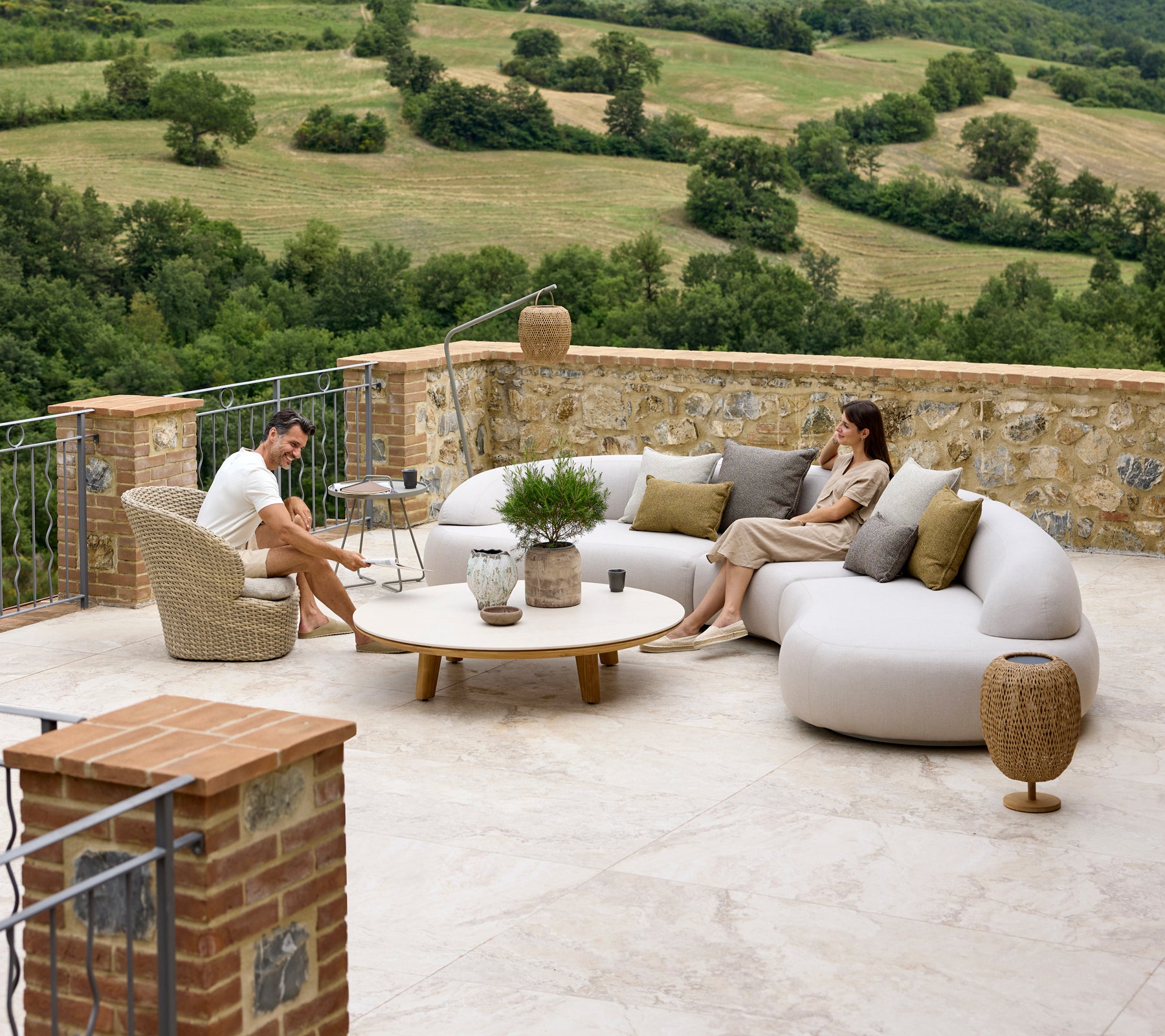 Avslappende sittearrangement med en myk lounge-sofa, Coast-lounge stol, Aspect kaffebord og Illusion Glow aksenter med en naturskjønn bakgrunn.