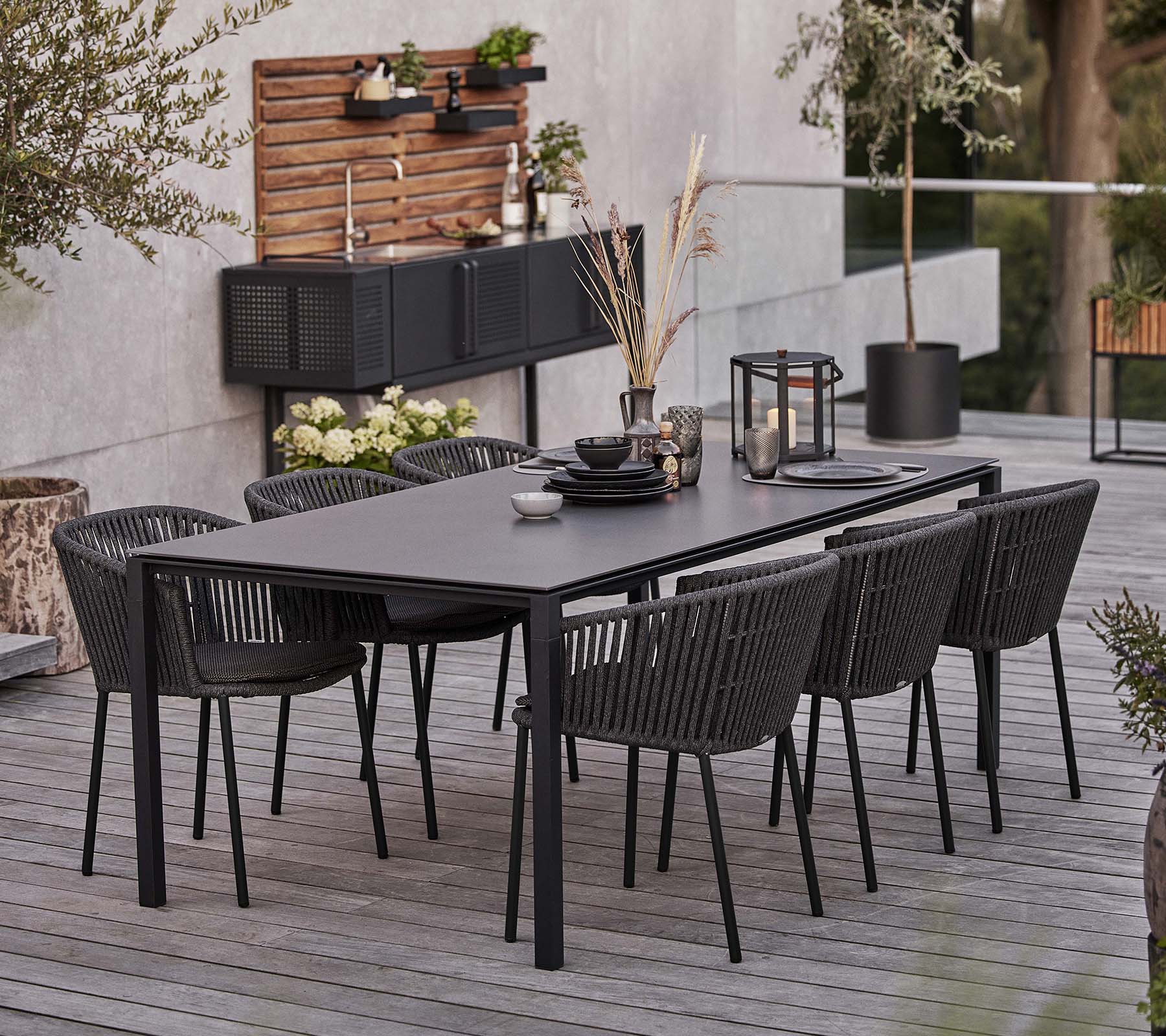 Et elegant svart bord med seks Moments-stoler, med servise og dekorative elementer for en innbydende spiseopplevelse.