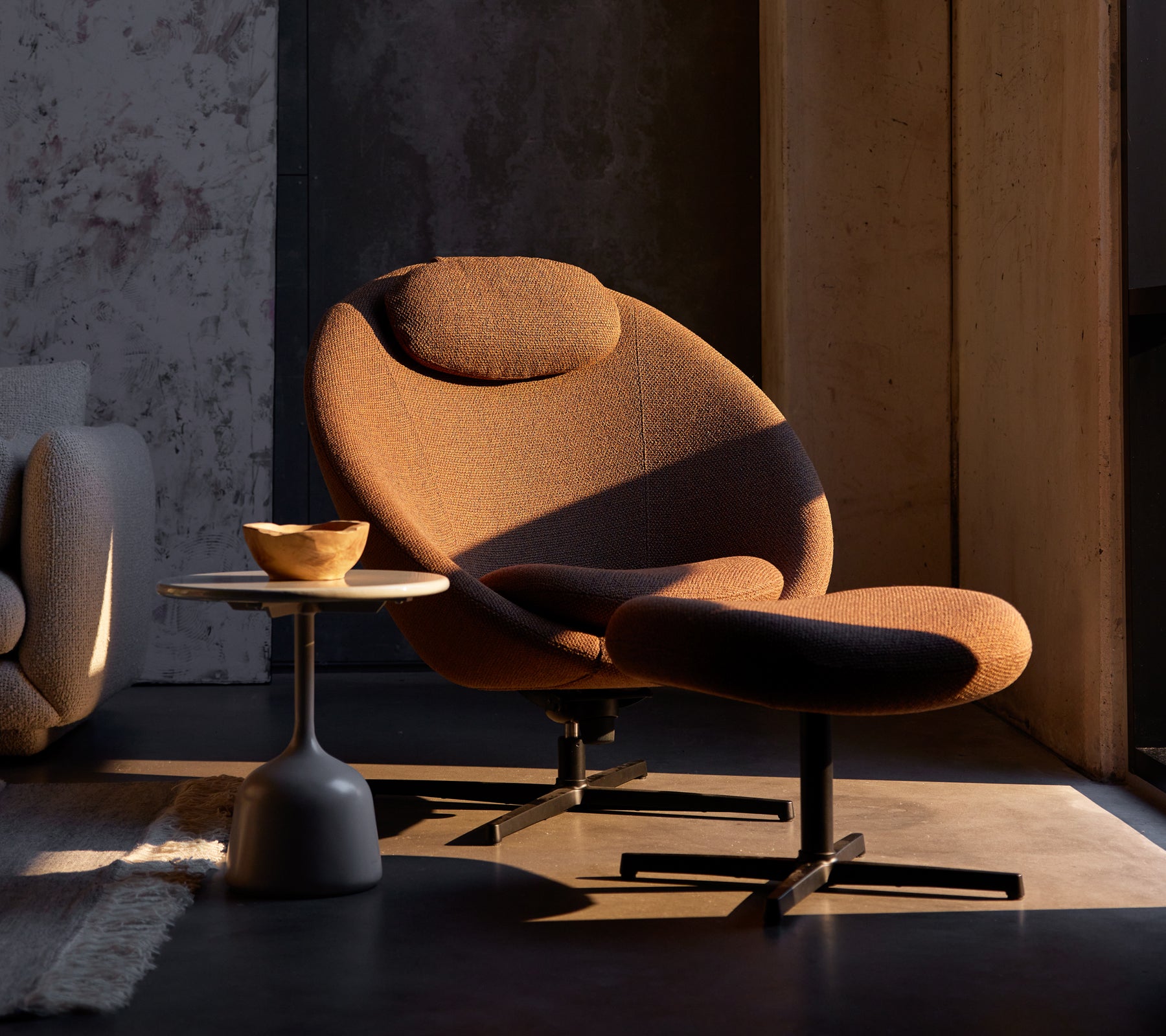 Umber brun Pace-stol med en matchende fotpall, supplert med et lite sidebord som har en trebolle.