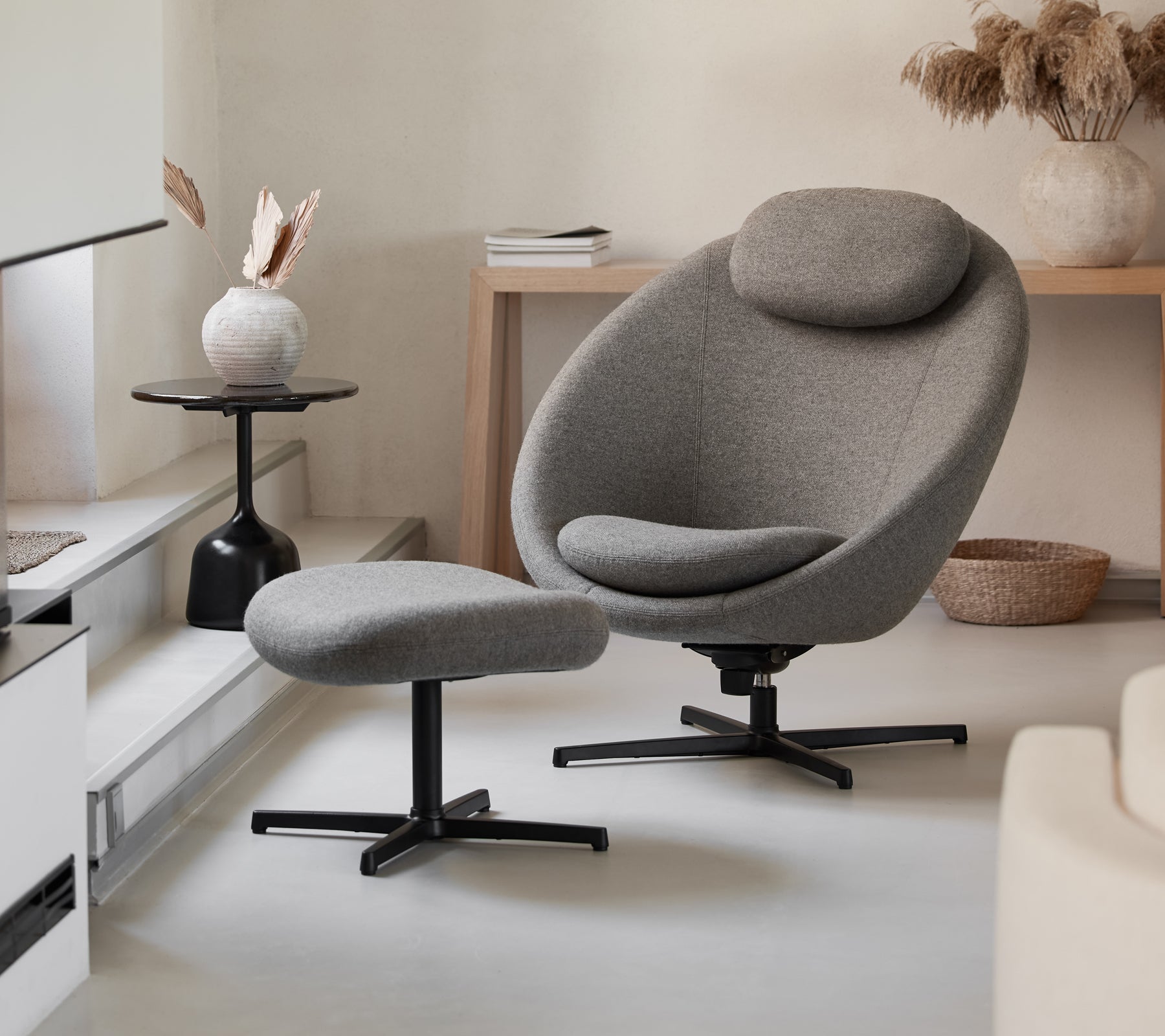 Stilig grå stol med matchende puff, med et strømlinjeformet design og komfortable kurver, komplementert av moderne dekorative elementer.