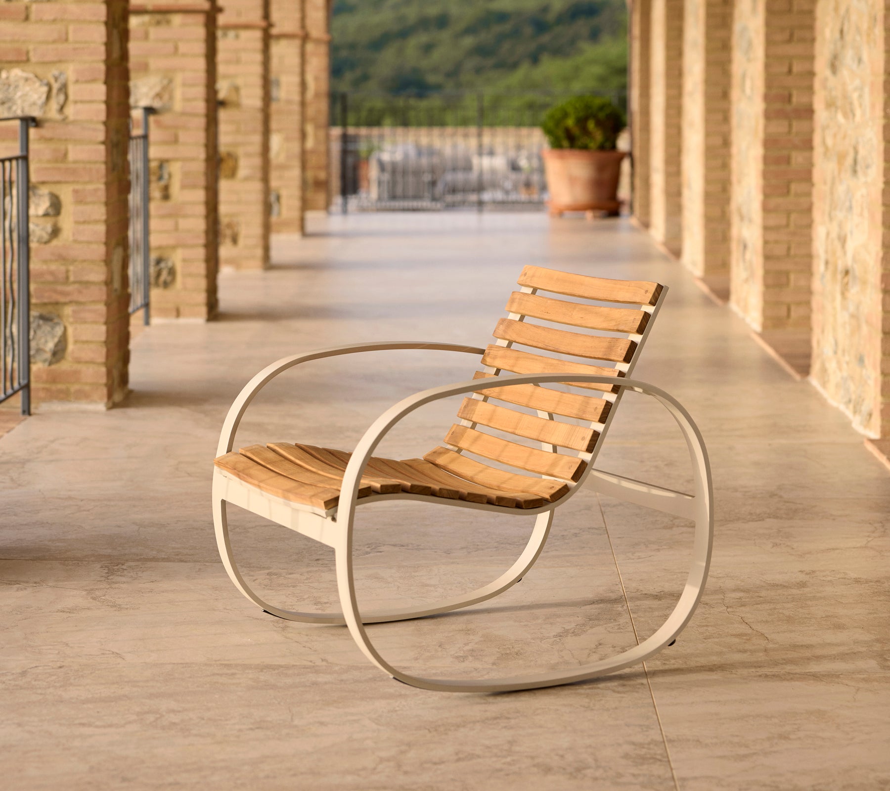 Parc gyngestol med aluminiumsramme og trelameller, plassert på en terrasse med steingulv og vakker bakgrunn.