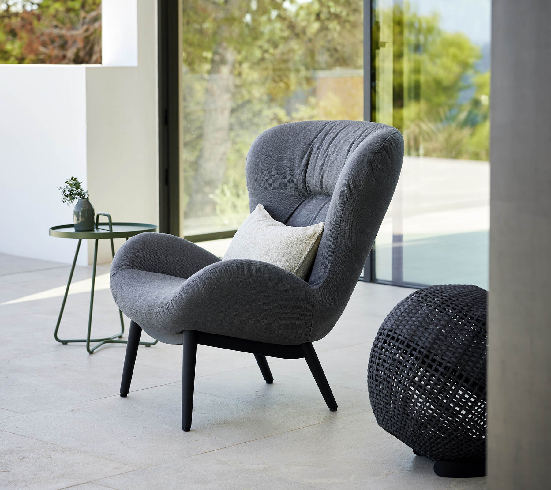 en rolig lenestol med moderne design, som har myk polstring og elegante ben, ledsaget av et lite sidebord og dekorative detaljer.