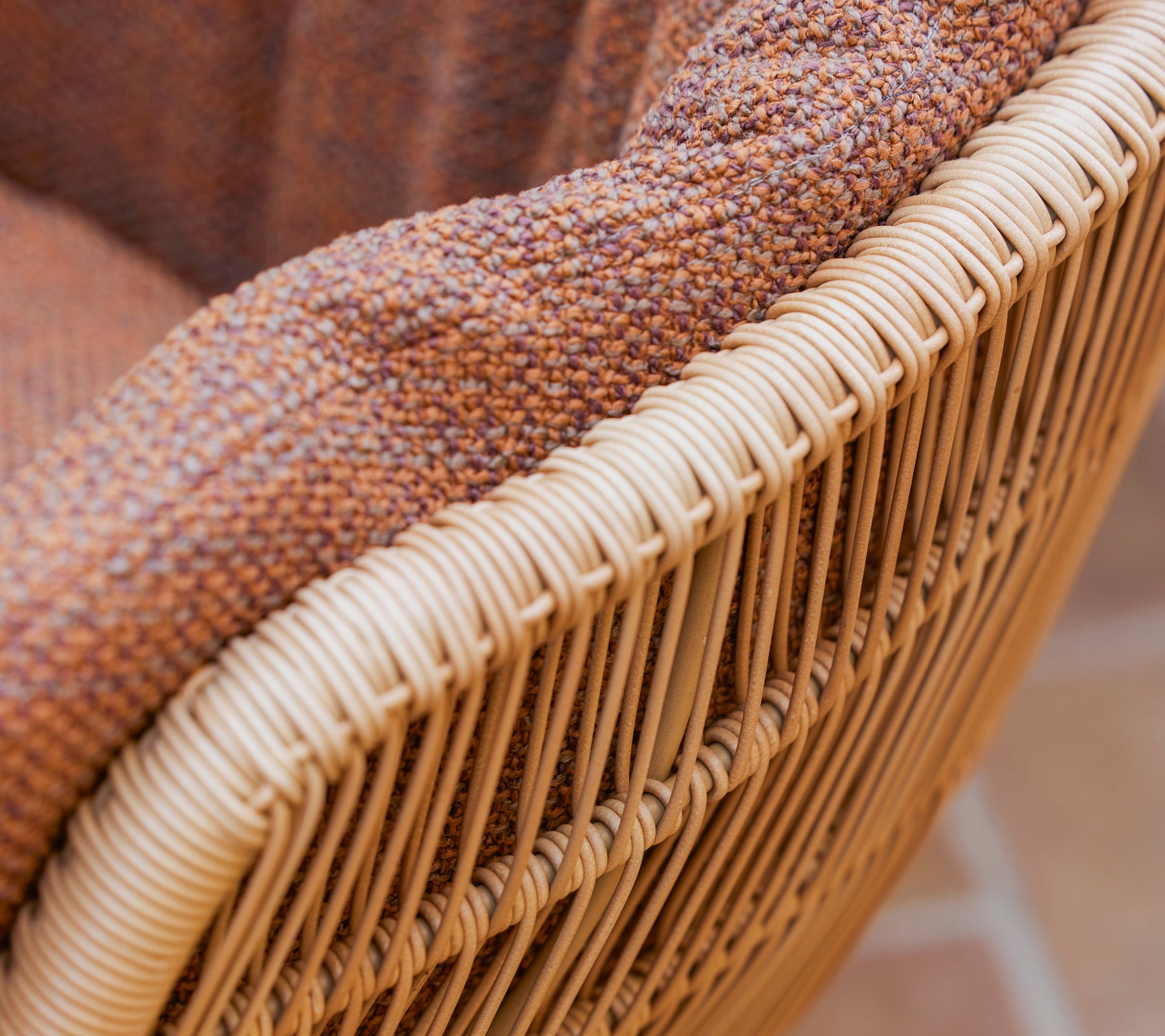 Nærbilde av en Stay spisestol med en teksturert brun Rise pute og en vevd ramme av naturlige fibre.