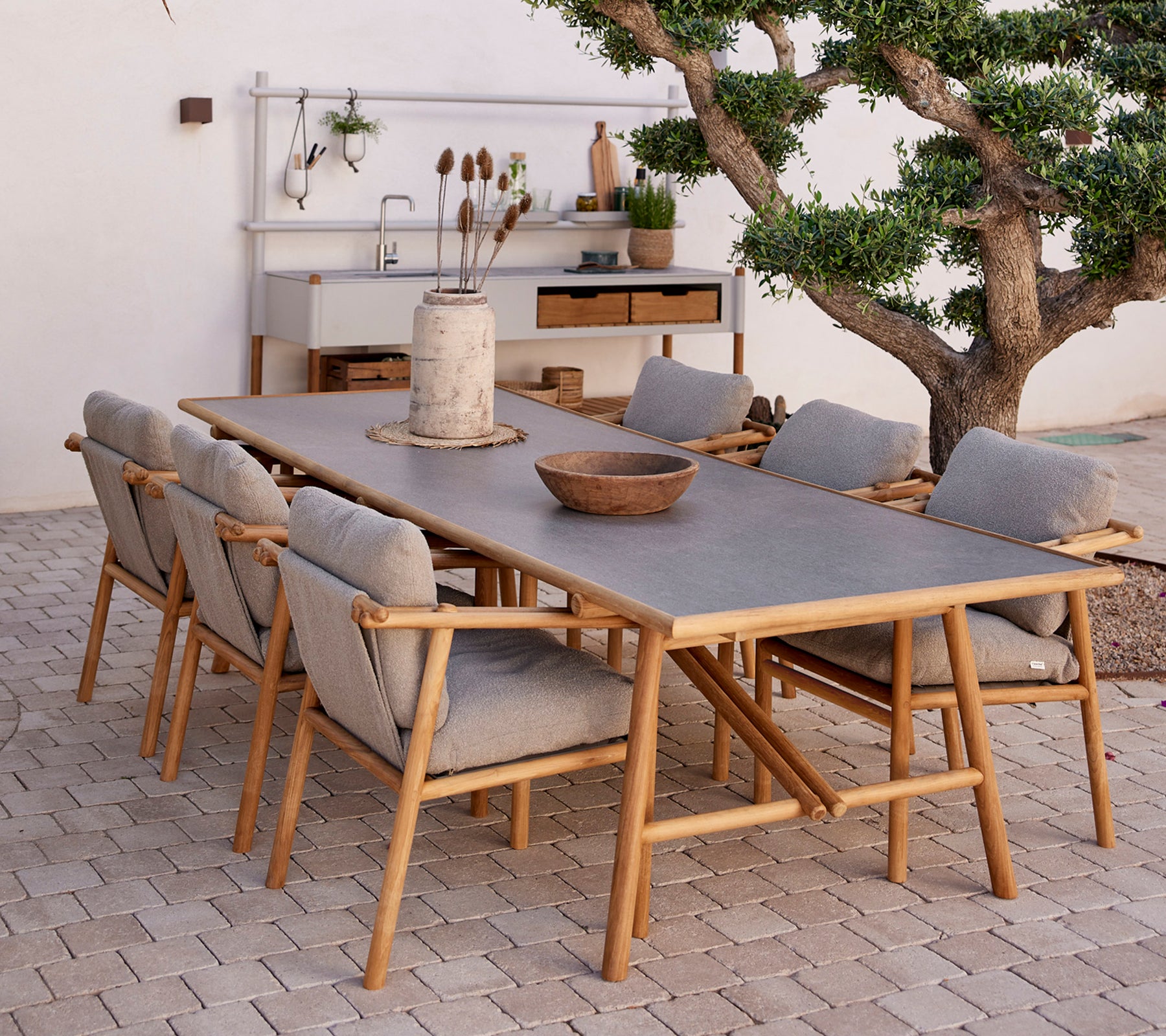 Teak spisebord omgitt av komfortable stoler, med naturlige elementer og en minimalistisk dekorstil.