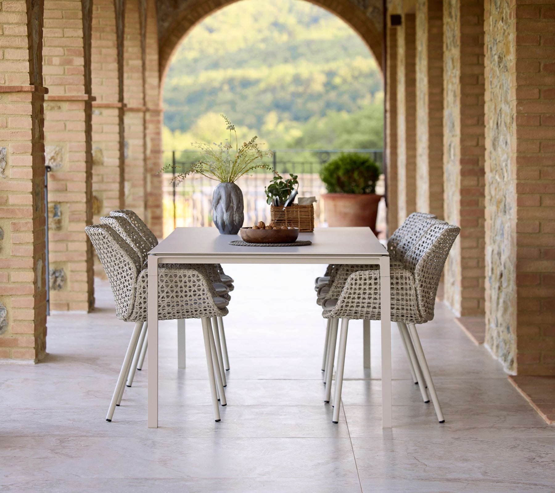 Elegant spiseoppsett med et Pure sand spisebord omgitt av Vibe spise Stoler, aksentuert med en vase og dekorative elementer.