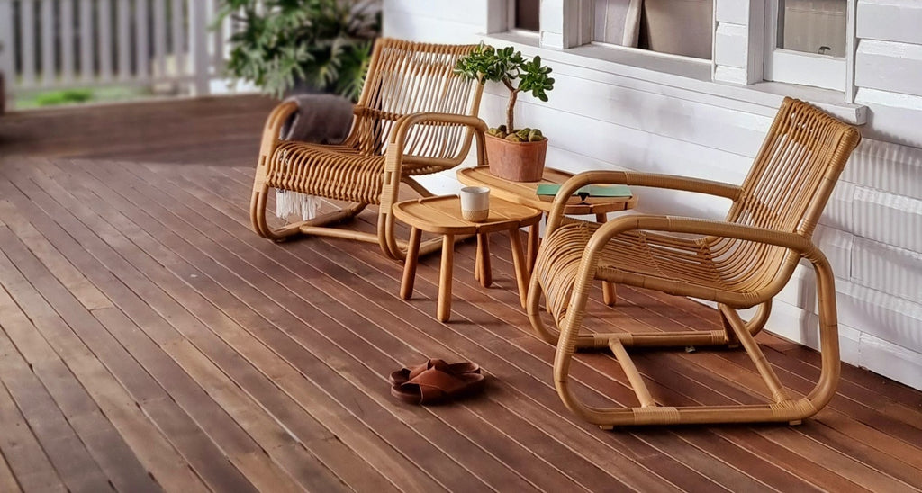 Lounge stole i neutral farve med teak træs sideborde på en veranda