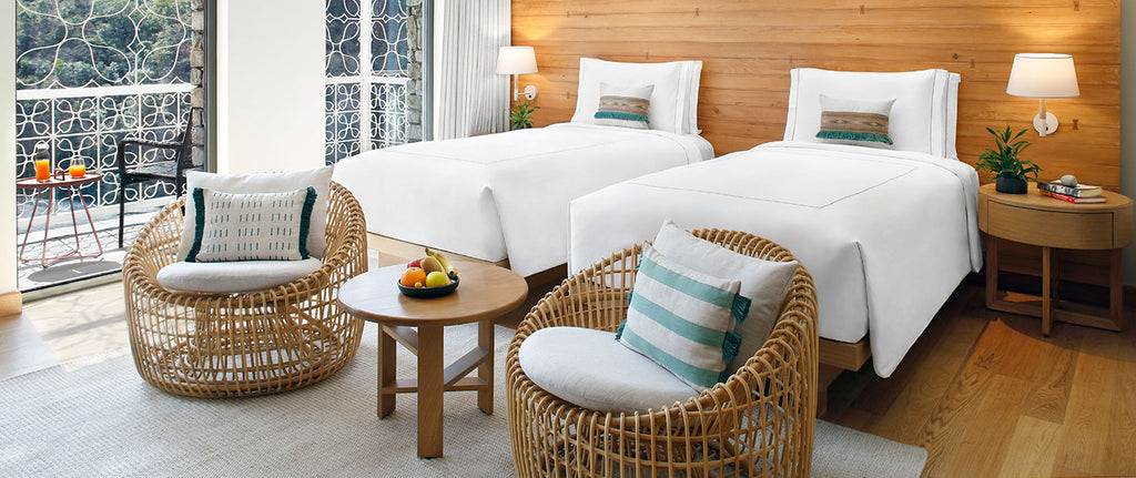 Hotel bedroom interior with two beds and Cane-line Nest lounge chairs