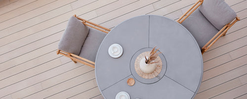 Rund spisebord med myke sitteplasser, komplementert av dekorative tallerkener og et midtpunktarrangement. Enkelt, elegant design.