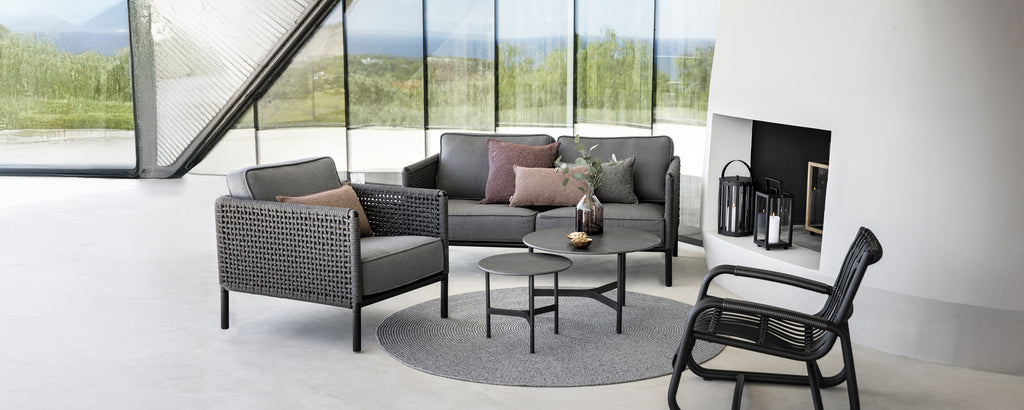 Moderne loungeområde med en grå sofa, svart lenestol og rundt salongbord.