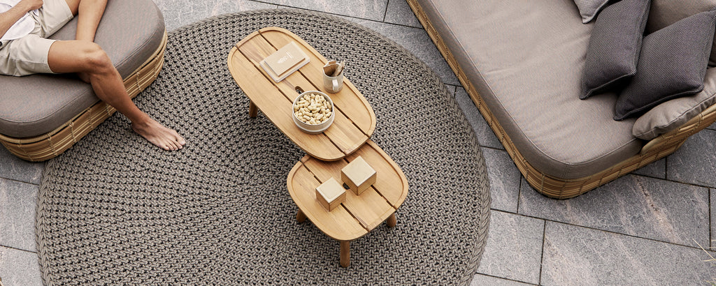 Moderne stueinnredning med et brunt kaffebord, en grå sofa og beige puter.