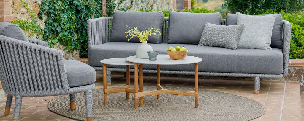 Moderne ute-loungeområde med en grå sofa, grå stol og et trebord.