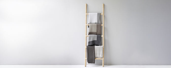 Moderne håndklestige som viser beige, grå og hvite håndklær.