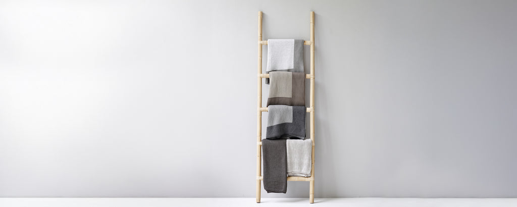 Moderne håndklestige som viser beige, grå og hvite håndklær.