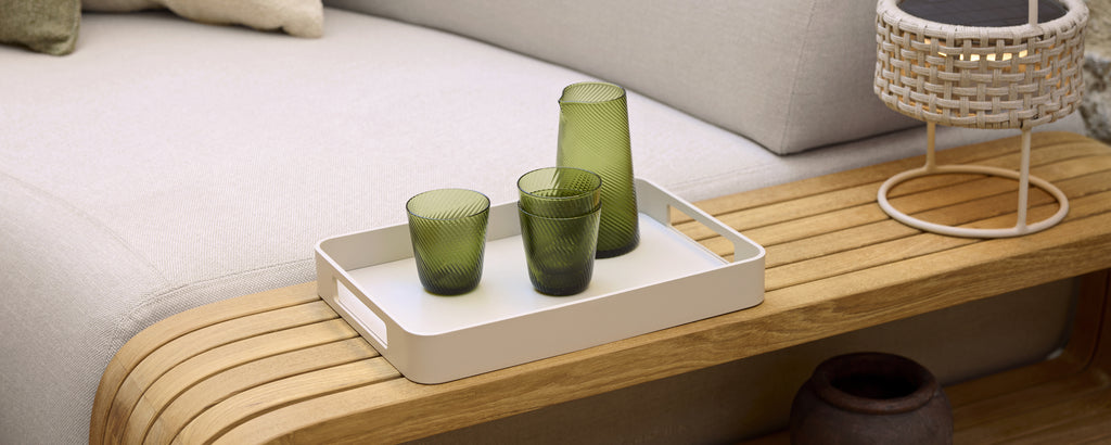Moderne loungeinnstilling med grønt glass på et hvitt brett.