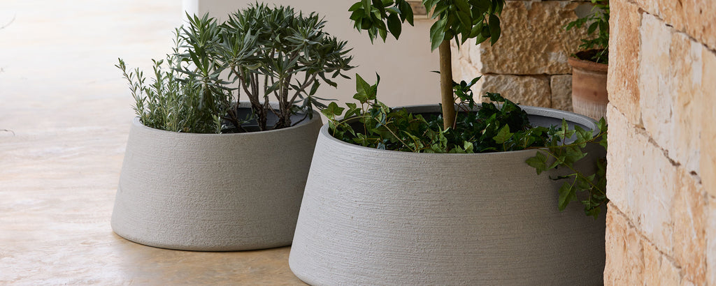 To moderne grå planter med grønt i en utendørs setting.