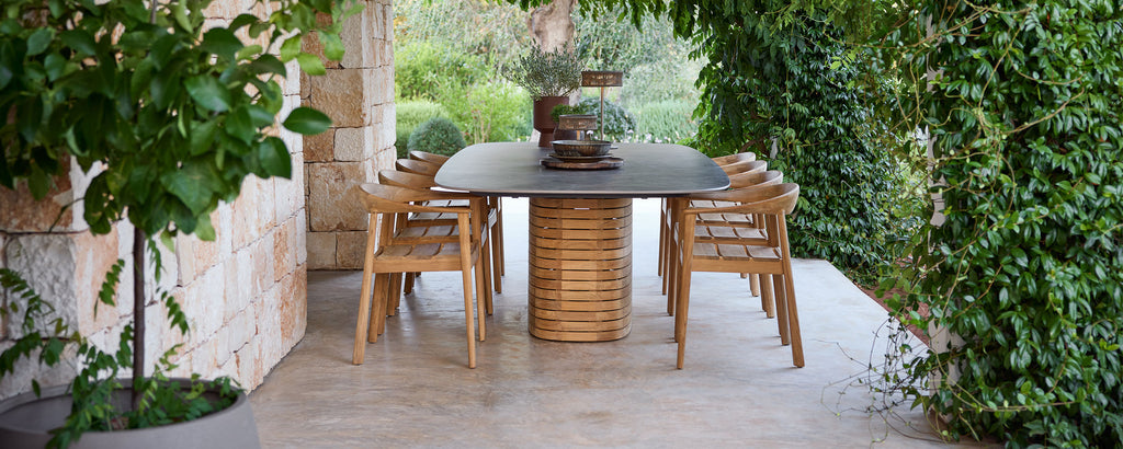 Utendørs tremøbler rundt et svart bord i en grønn hage.