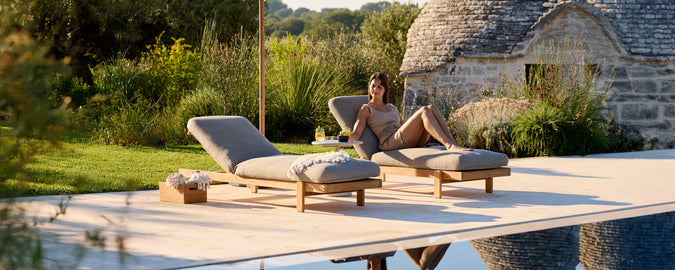 Contemporary grey lounge chairs by a pool in an outdoor setting.