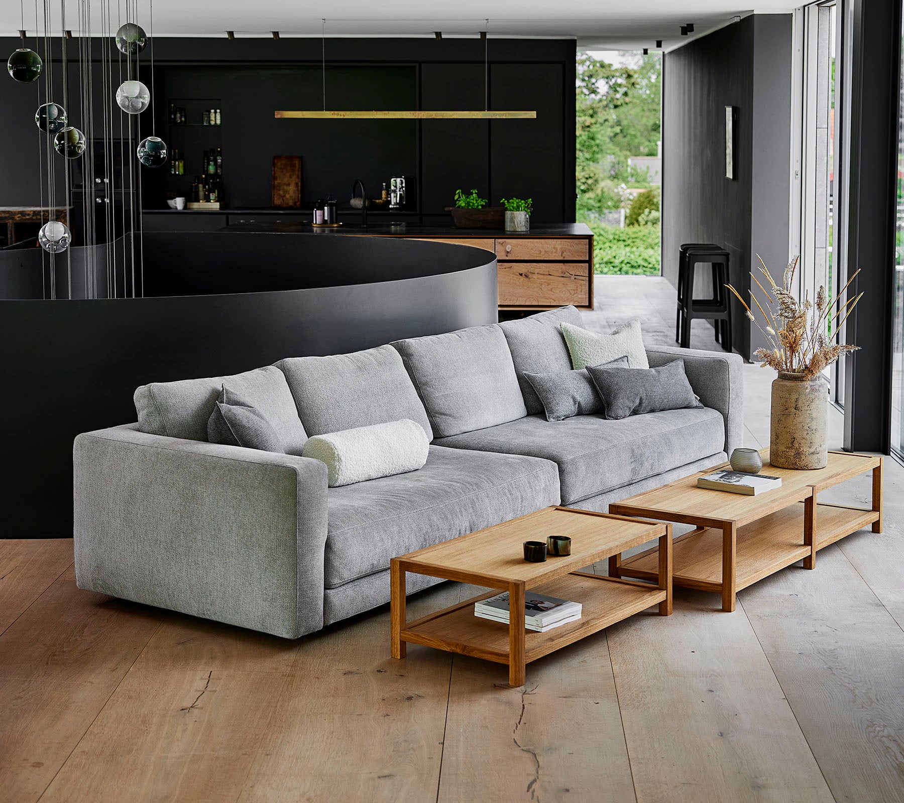 En moderne, grå sofa med myke puter ved siden av trekaffebord i en moderne setting med stilfull dekor.