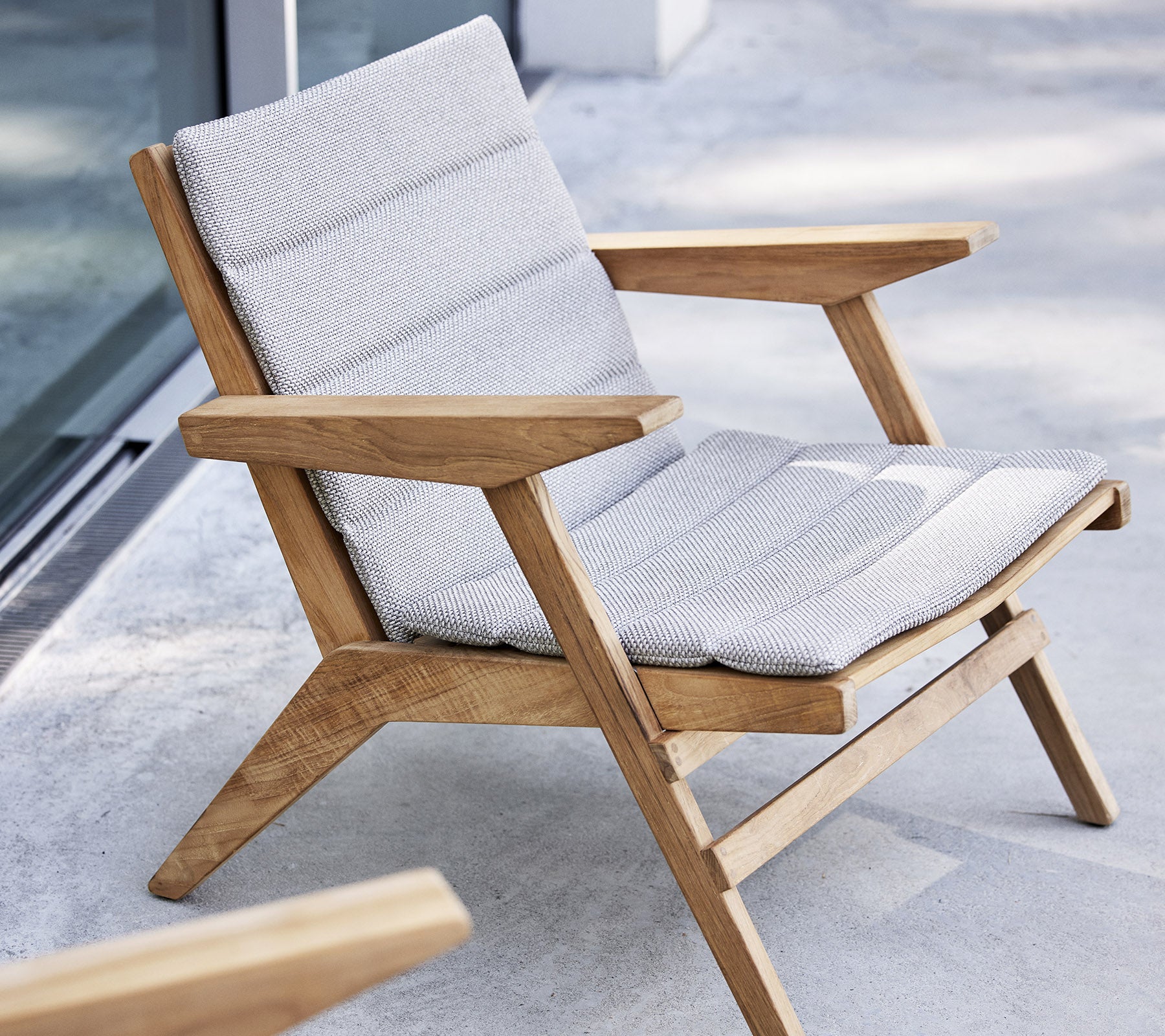 Stilig lenestol med tre ramme og polstret sete, designet for komfort og avslapning.
