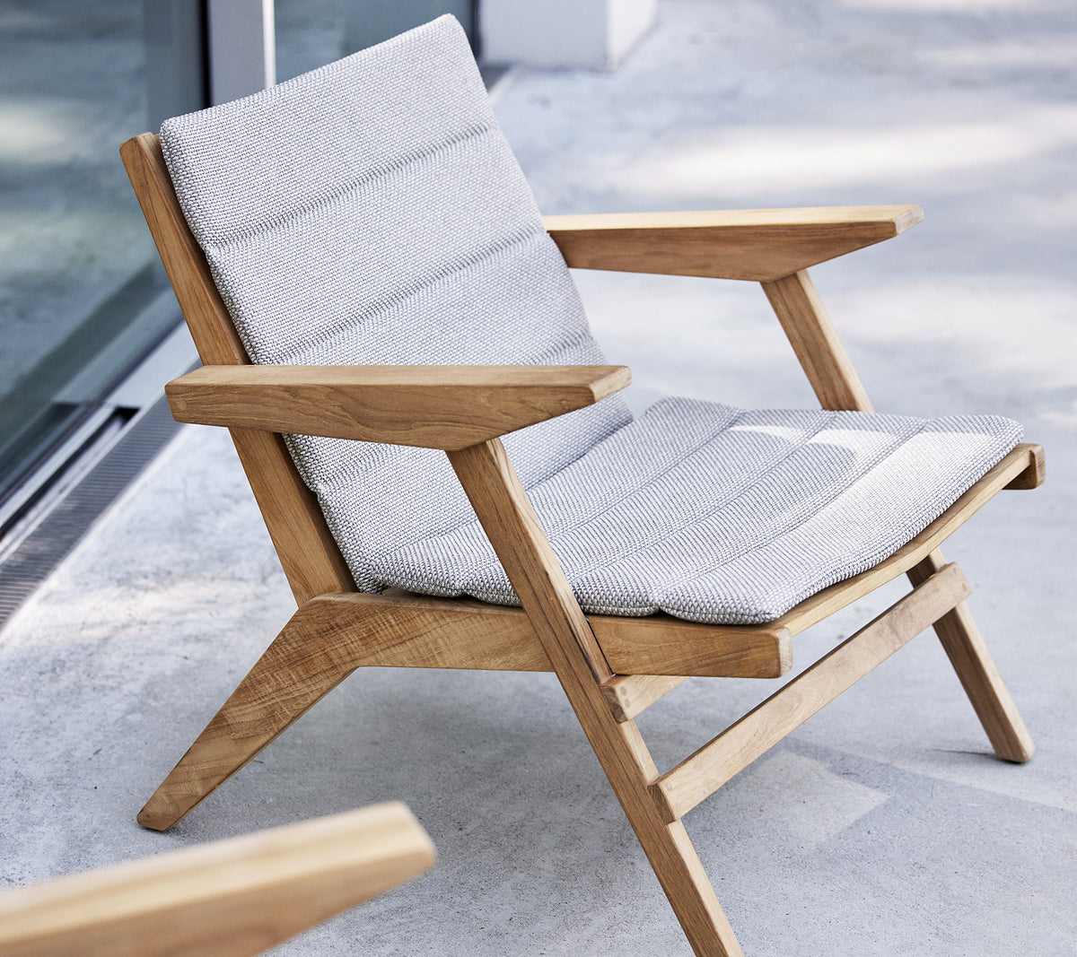 Stilig lenestol med tre ramme og polstret sete, designet for komfort og avslapning.