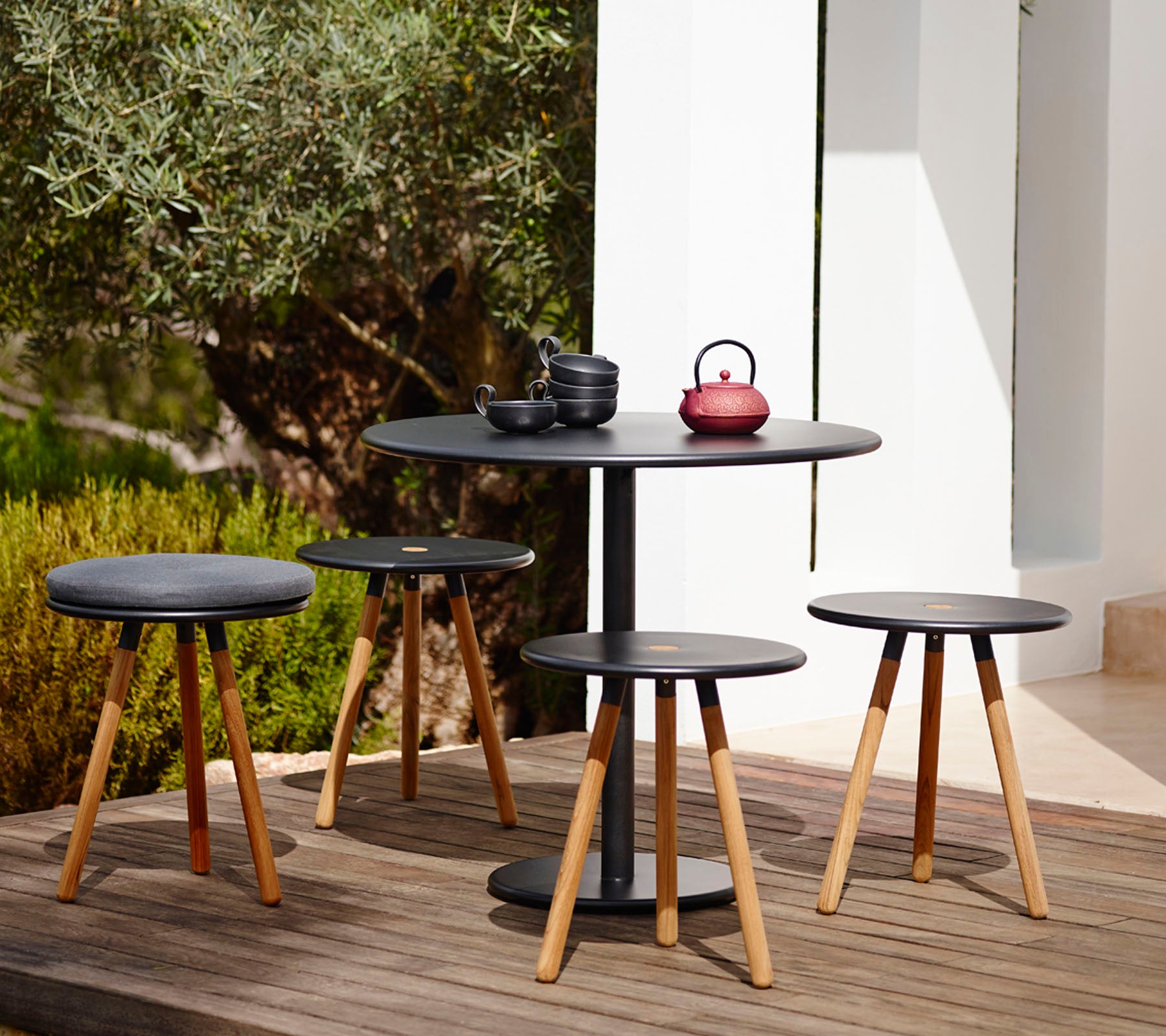 Moderne svart bord og stool-sett i en utendørs hageinnstilling.