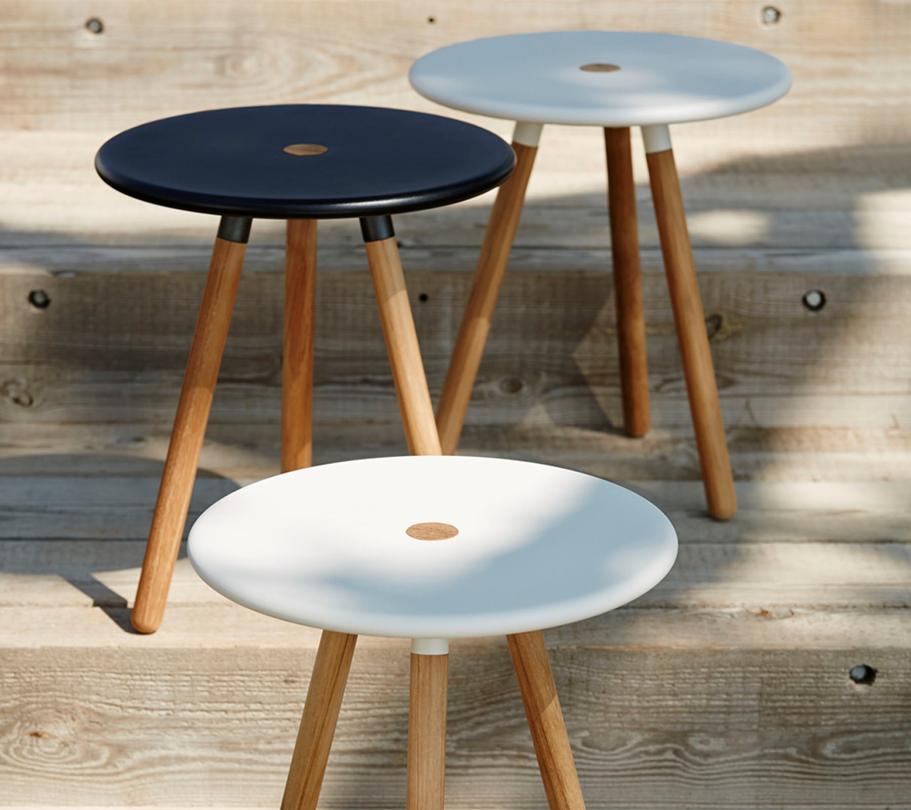 Tre minimalistiske krakker med runde topper i svart og hvitt, hver støttet av trebein, som fremhever et moderne og stilrent design.