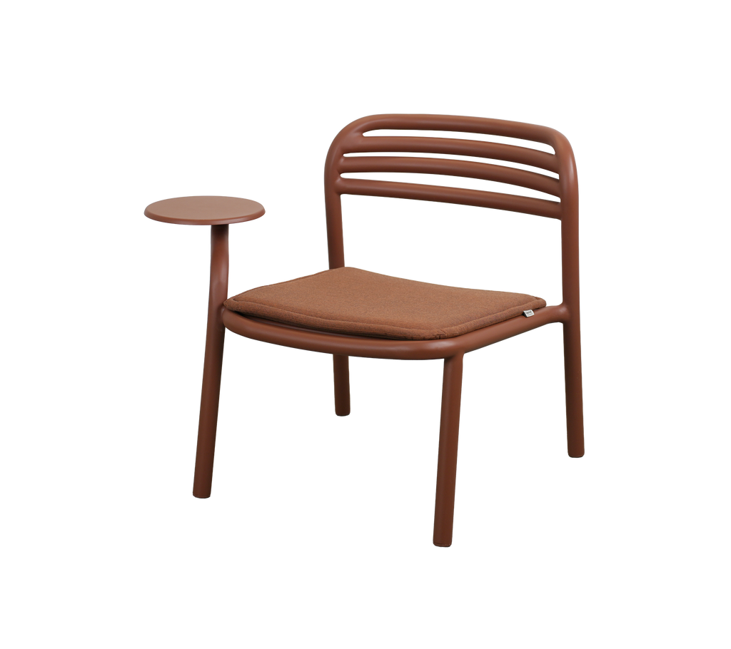 Moderne stol i ørkenrød med et lite sidebord.