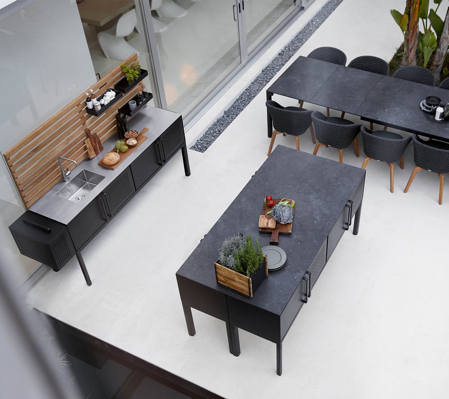 Moderne uteromkjøkkenoppsett med en stilren benkeplate, rommelig spisebord og stilige sitteplasser med planter og dekorative elementer.