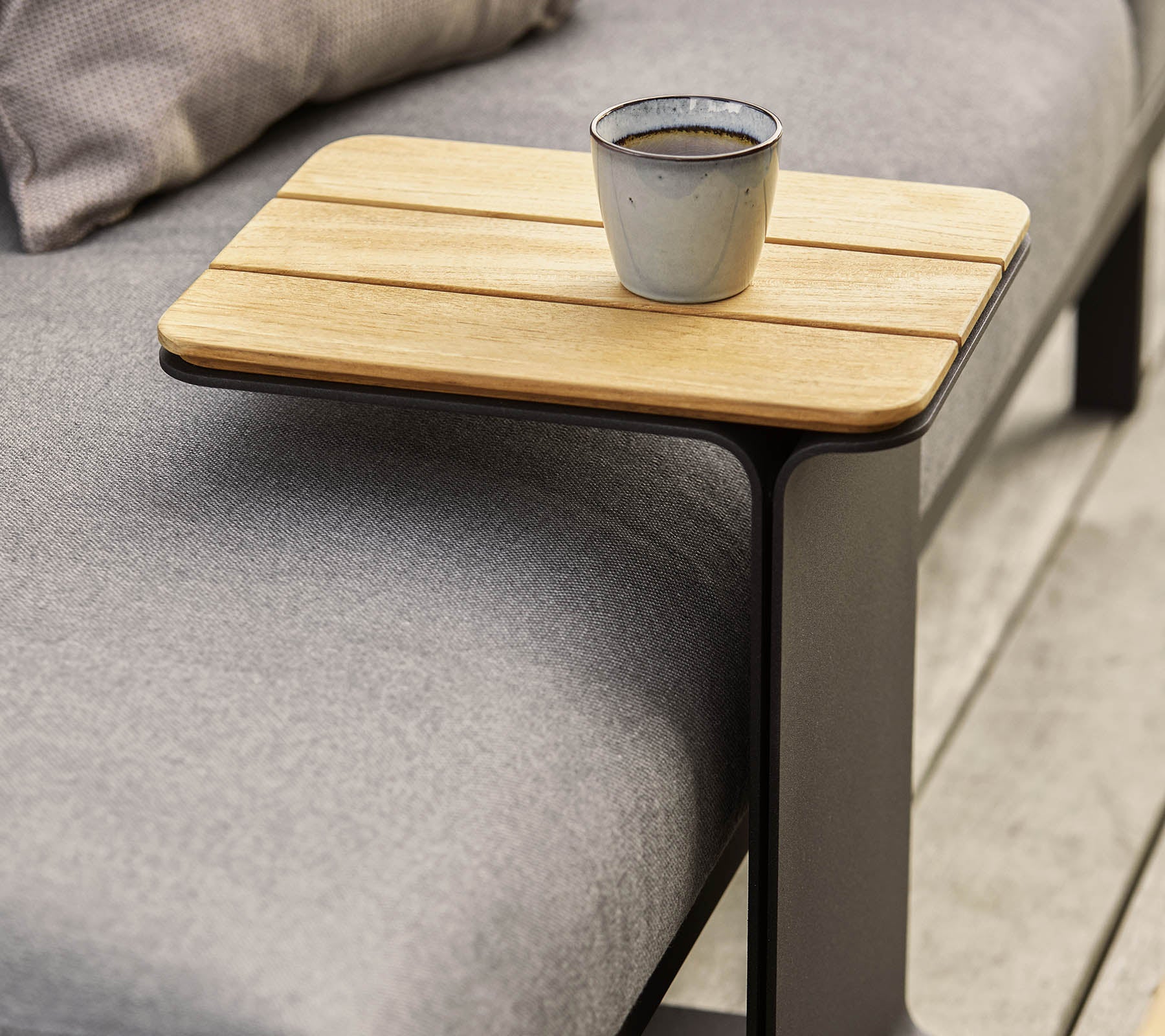 Et strømlinjeformet sidebord med en treoverflate og en moderne metallramme, med en liten kopp plassert på det.