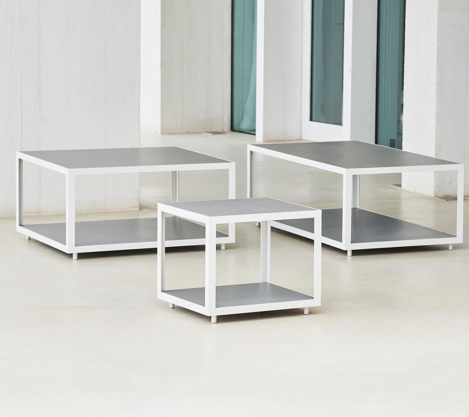 Et sett med tre moderne bord med et smakfullt design som har metallrammer og flate overflater, ordnet i varierende størrelser.