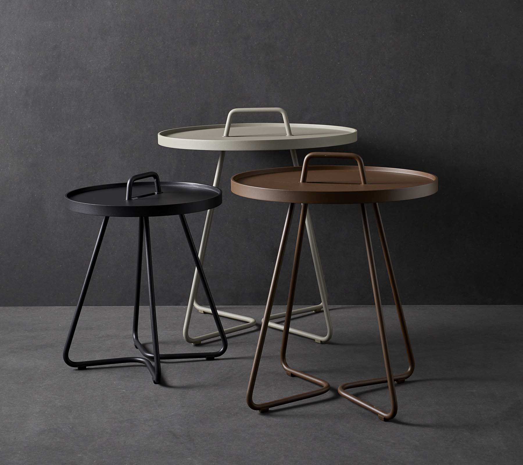Tre stilige sidebord med runde topper og unike håndtakdesign, som har en blanding av farger inkludert svart, hvit og brun.