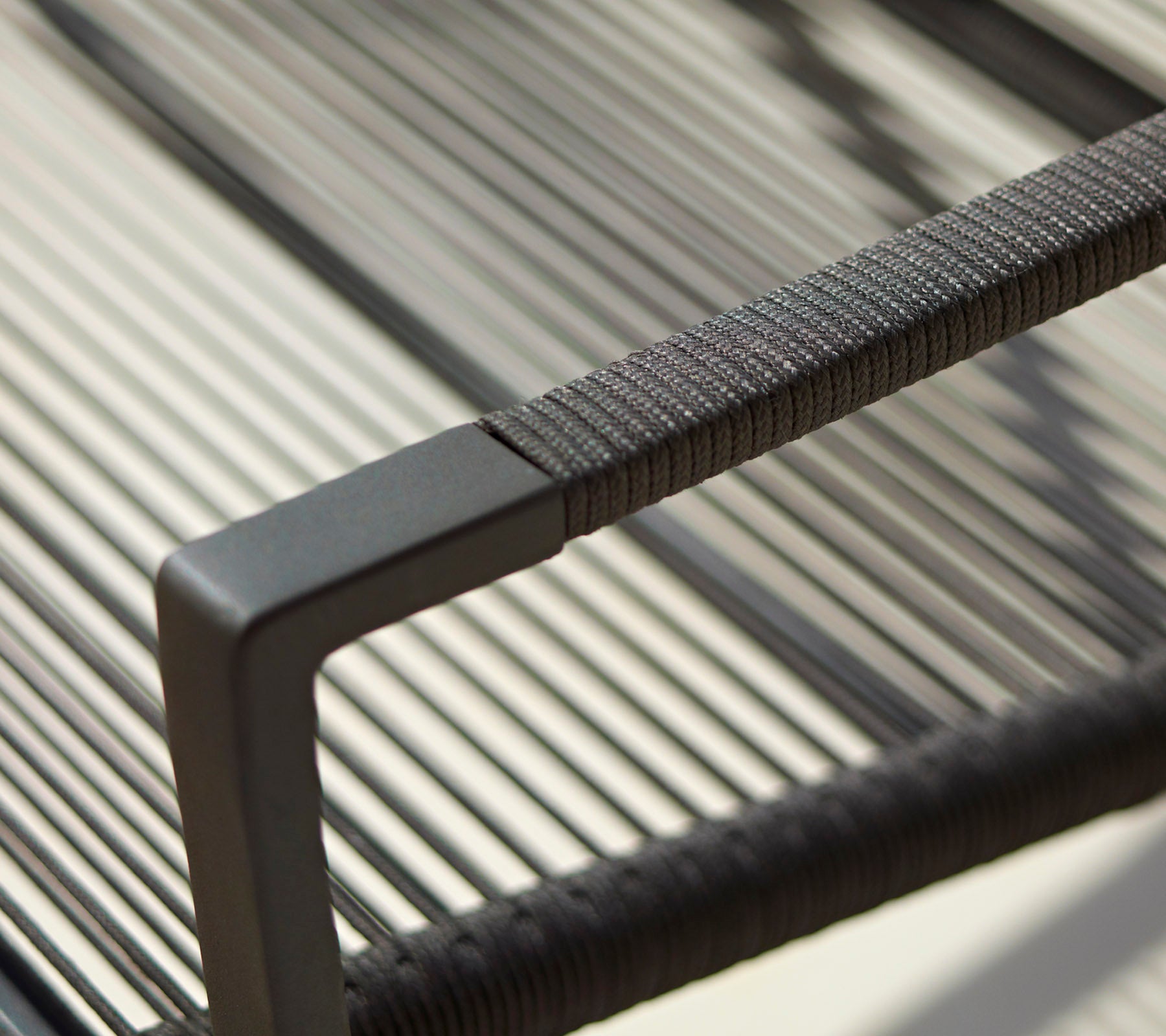 Nærbilde av et moderne stolarmstøtte med en strømlinjeformet design, teksturerte detaljer og en minimalistisk svart finish.