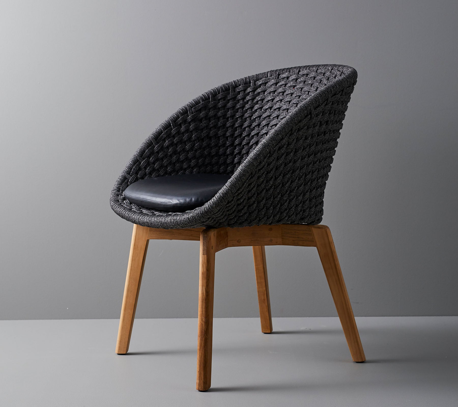 Stilig vevd stol med et komfortabelt pute, med glatte, avsmalnende treben og et moderne design som er passende for ulike omgivelser.